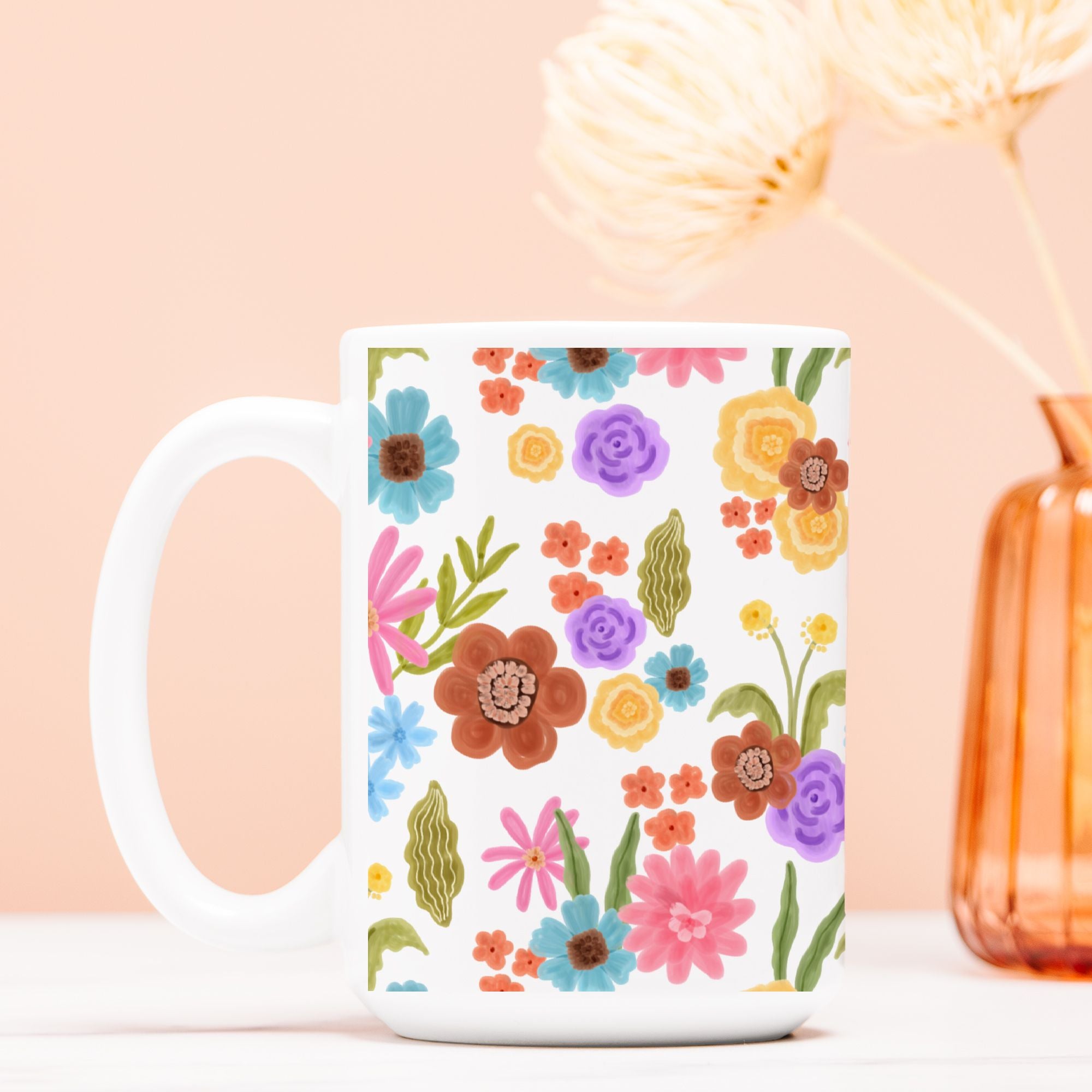 White mug with colorful floral pattern on a light pink background