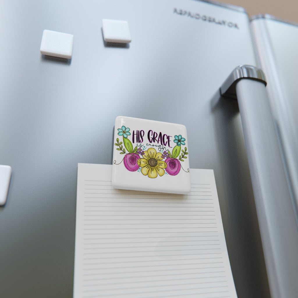 Decorative magnet with floral design and 'His Grace' text on a refrigerator.