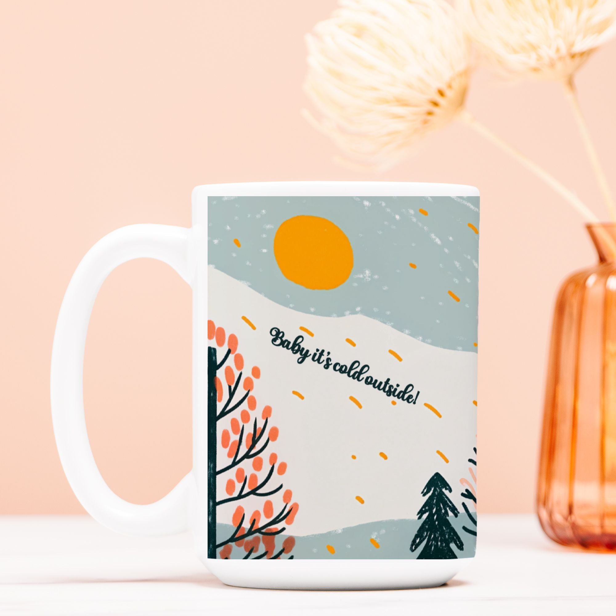 Mug with winter scene design and text 'Baby it's cold outside!' on a light pink background