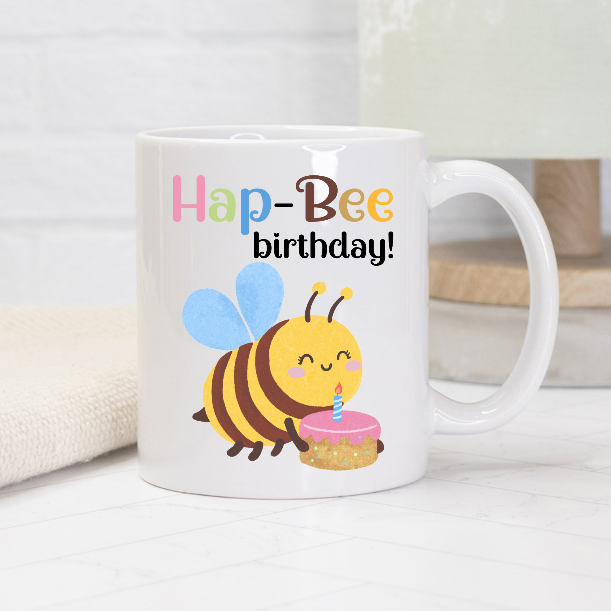 White mug with a bee design and 'Hap-Bee birthday!' text on a light background