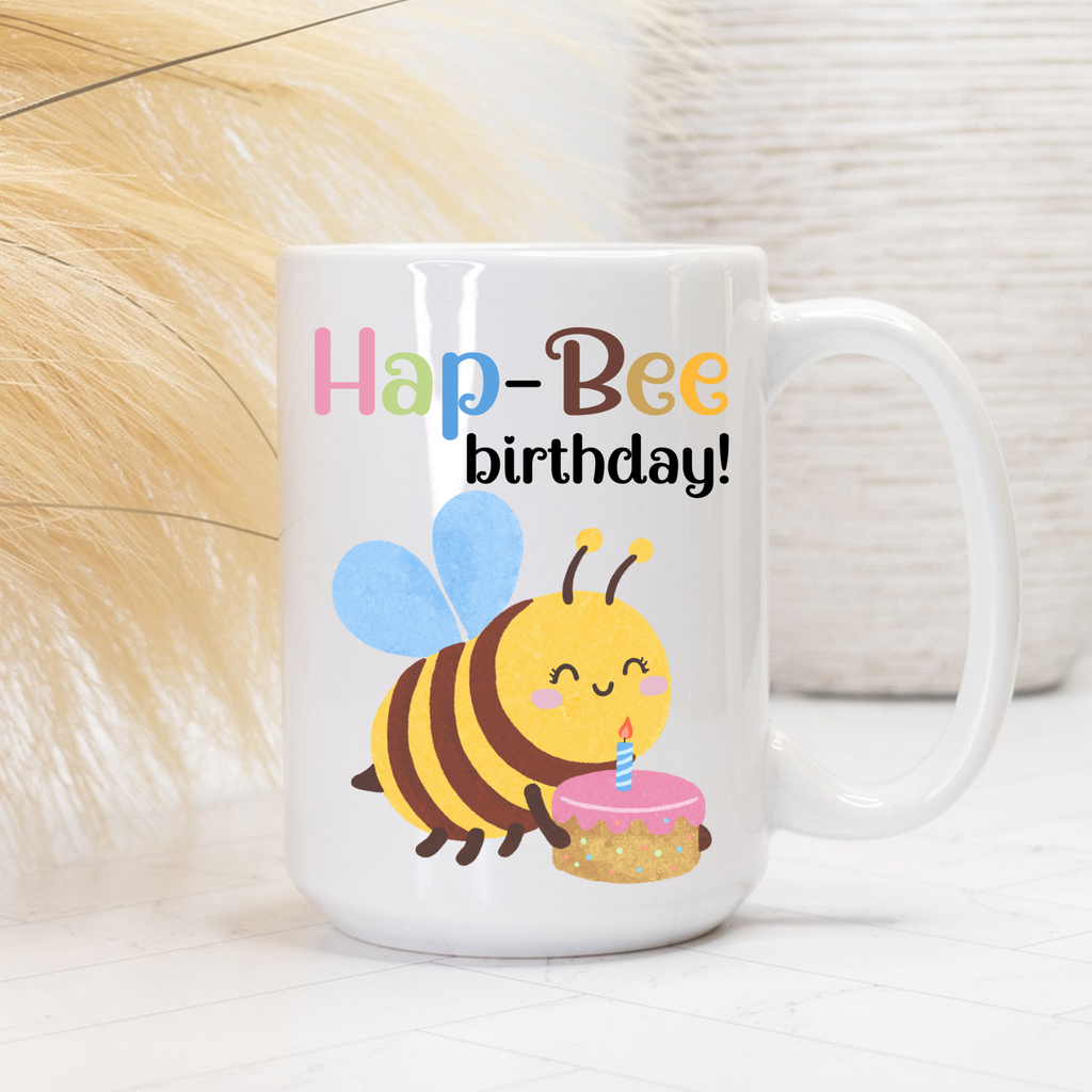 White mug with a bee design and 'Hap-Bee birthday!' text on a light background