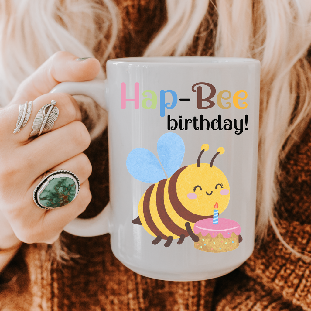 Mug with a bee design and 'Hap-Bee birthday!' text held by a person.