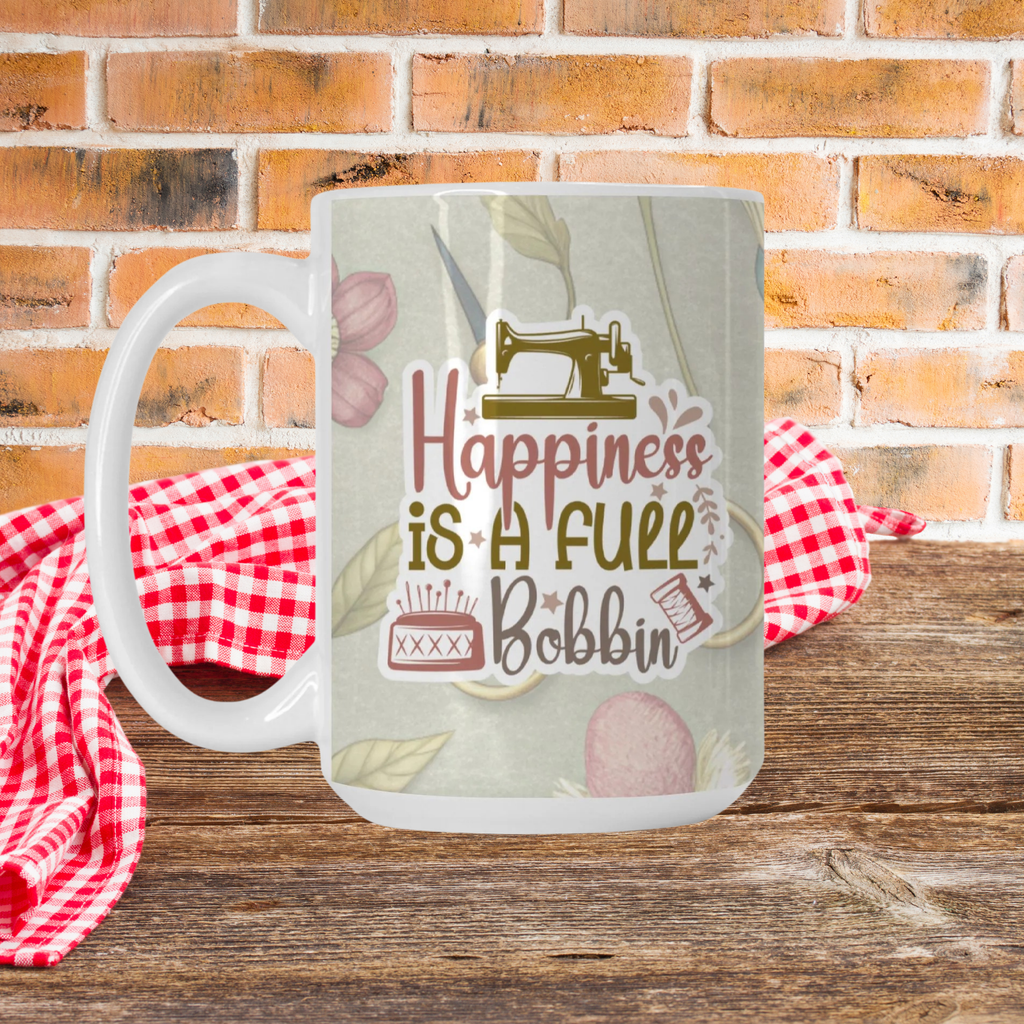 Mug with sewing-themed design and text 'Happiness is a Full Bobbin' on a wooden surface with a red and white checkered cloth and brick wall background.