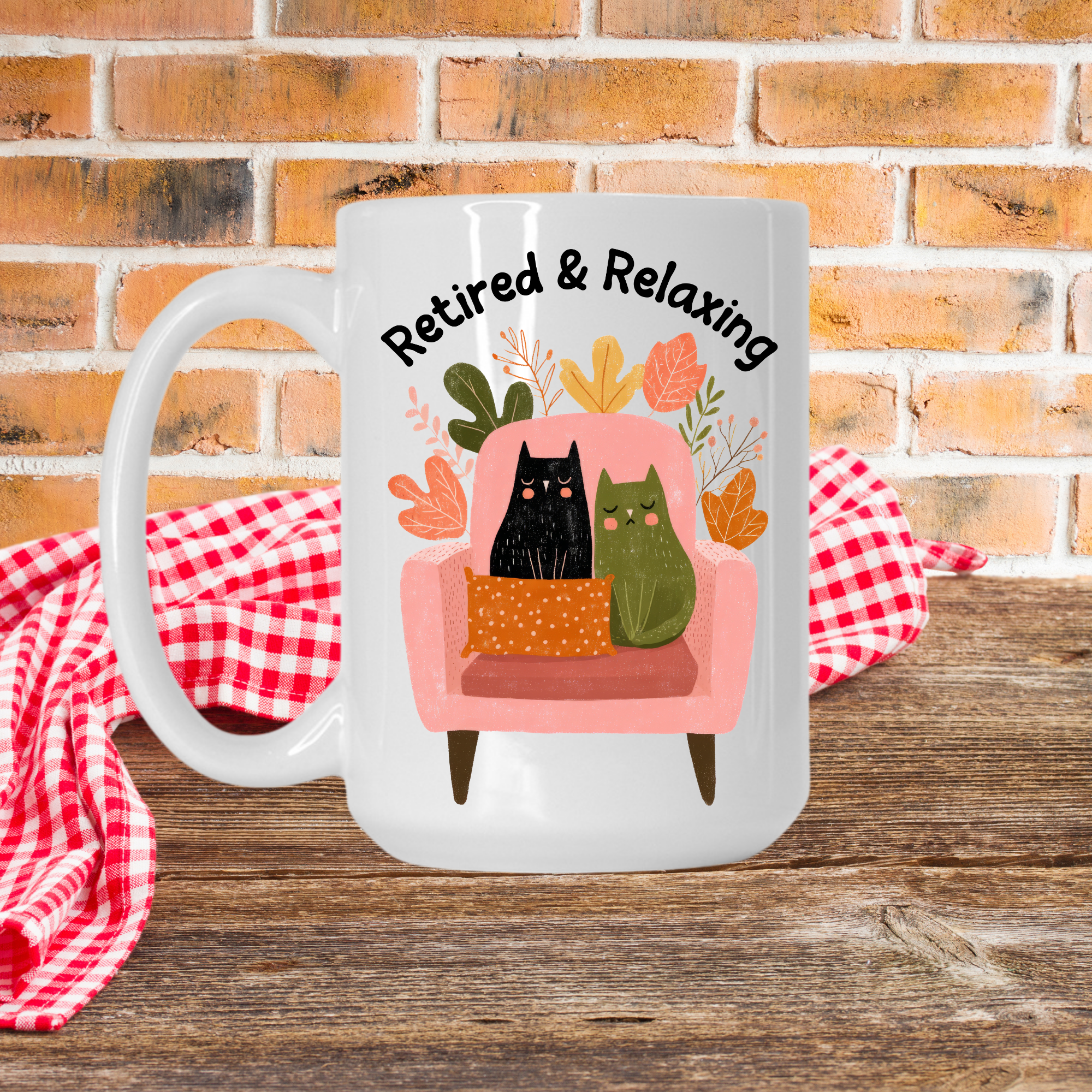 White 15oz. mug with a design of two cats on a chair and text 'Retired & Relaxing' against a brick wall background.