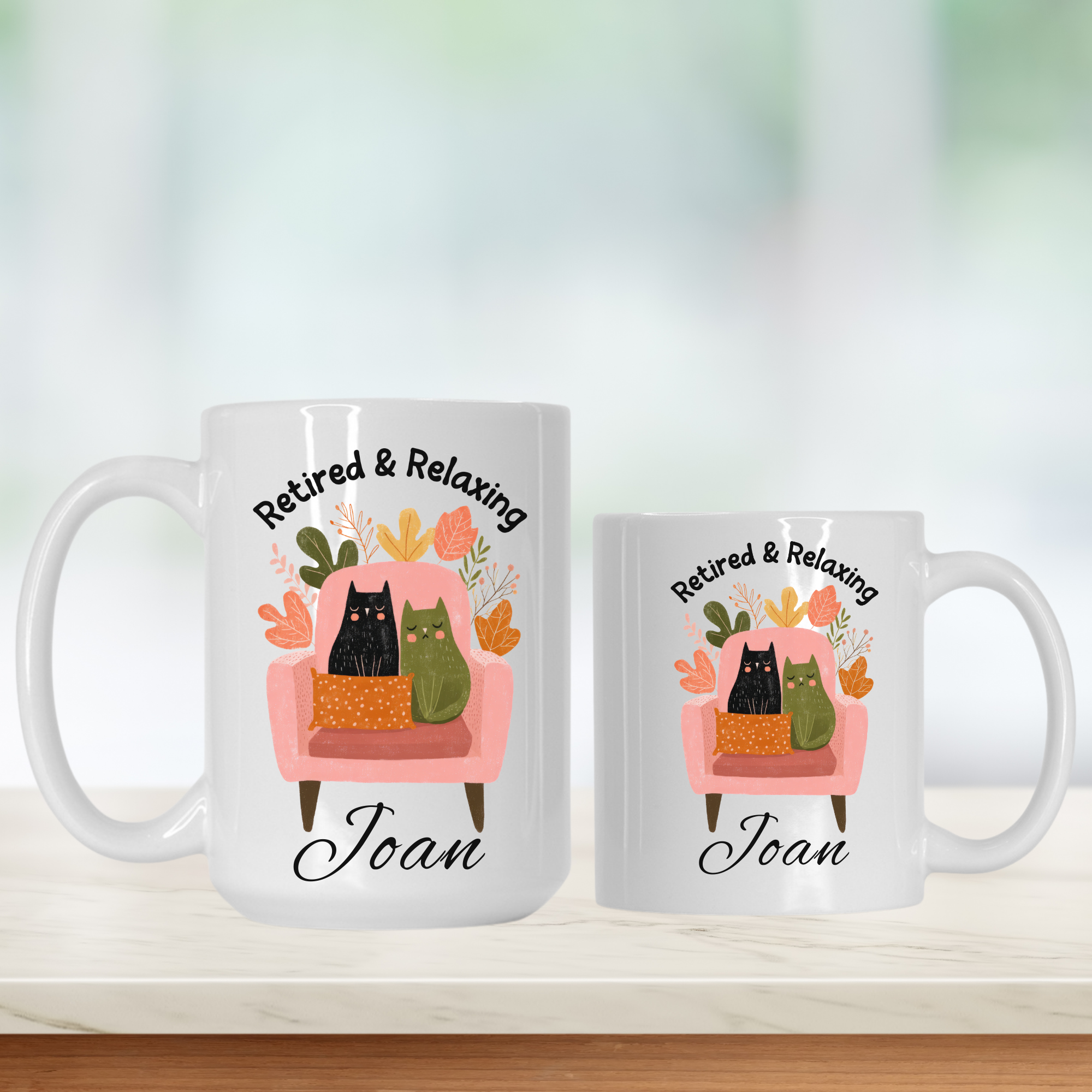 11oz. & 15oz. mugs with a design of cats on an armchair and text 'Retired & Relaxing Joan' on a white background.