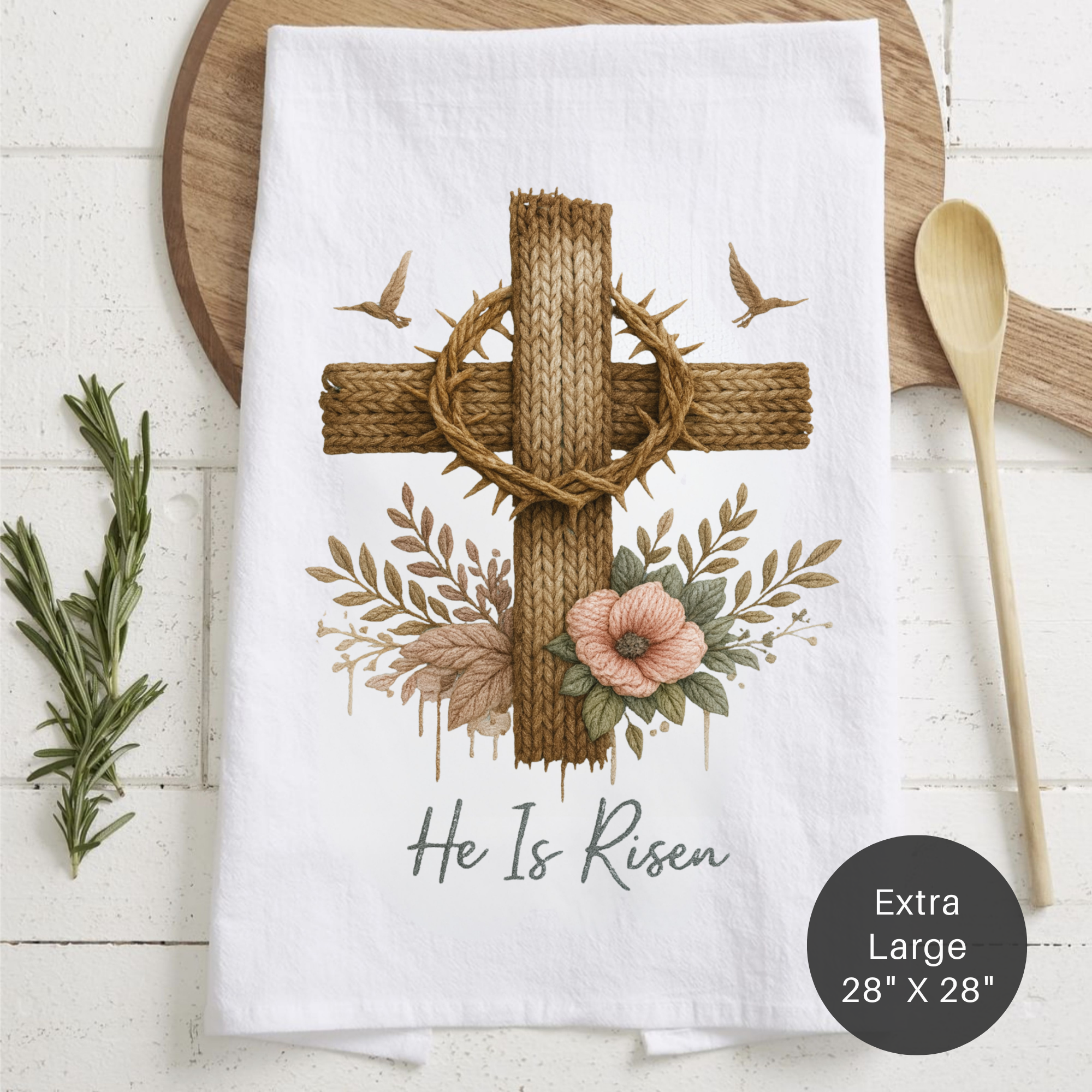 White towel with a cross and floral design, featuring the text 'He Is Risen' on a wooden surface.