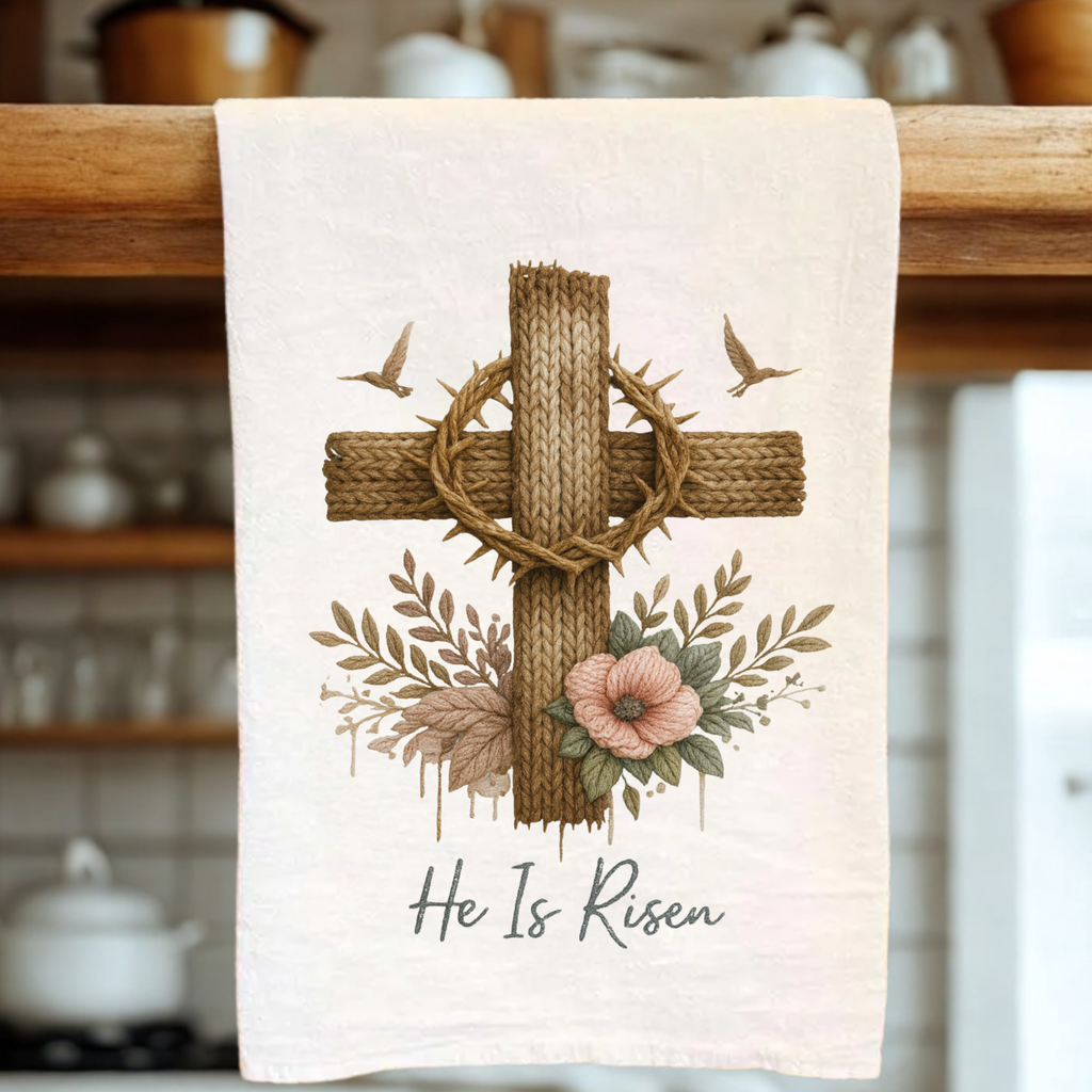 Tea towel with a cross, crown of thorns, and flowers design on a wooden rack.