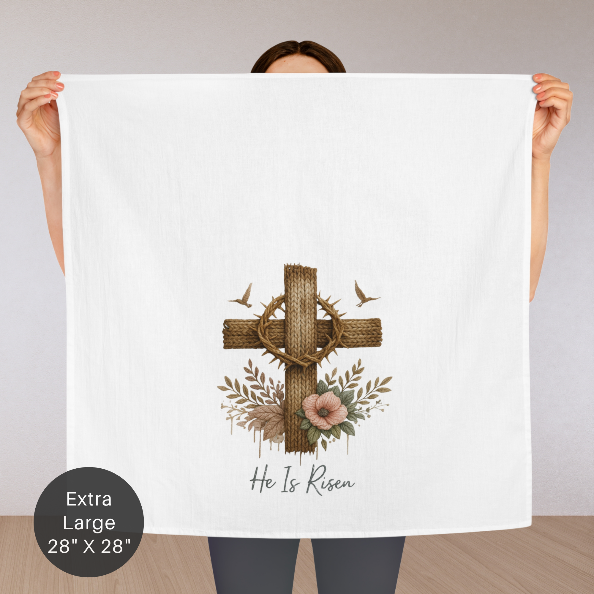 Person holding a large white tea towel with a cross, crown of thorns, and flowers design.