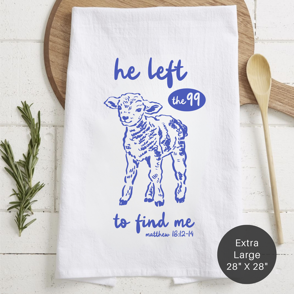 White towel with blue lamb illustration and text on a wooden surface