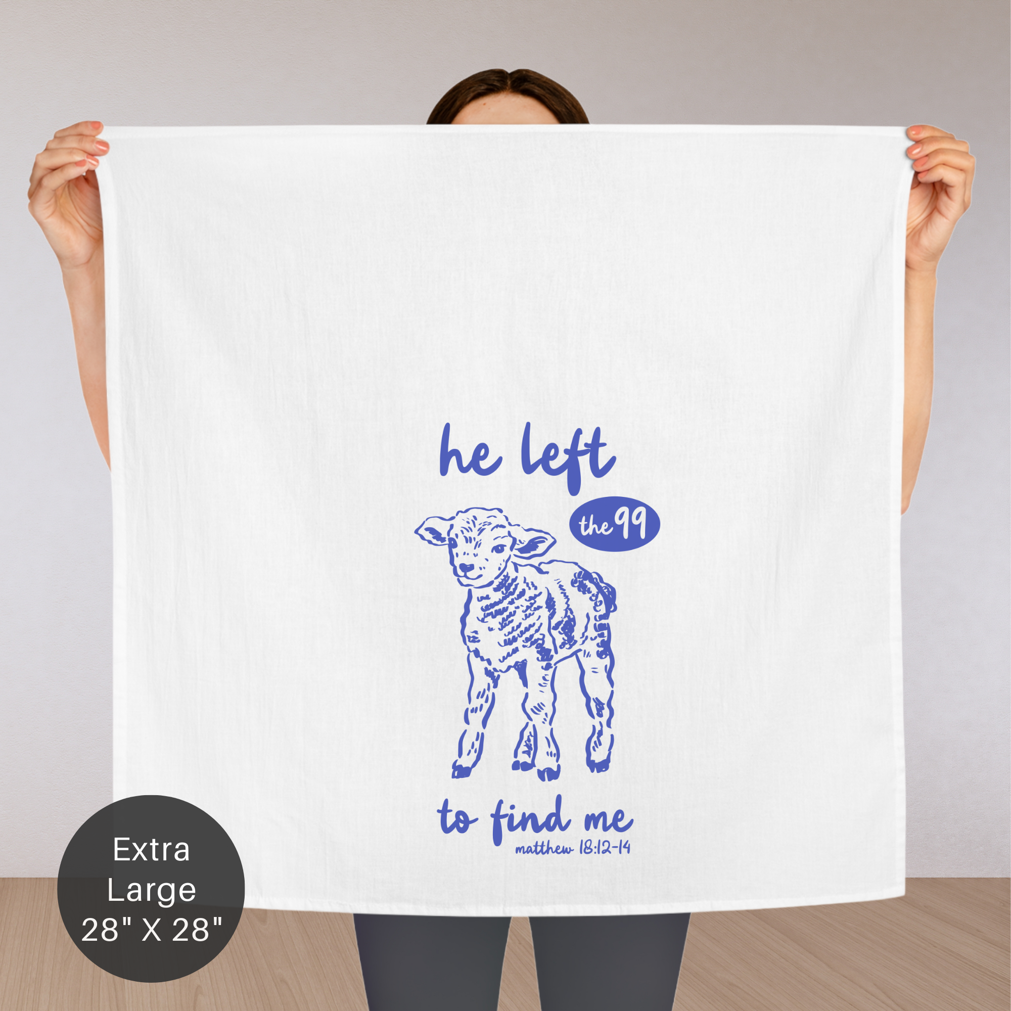 Person holding an extra large white tea towel with blue text and lamb illustration.