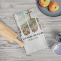 Folded tea towel with cross design and Bible verse on a wooden table with apples and a rolling pin.