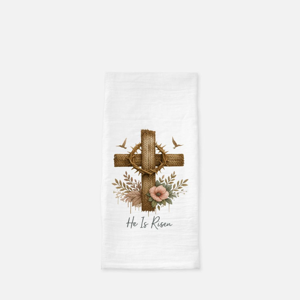 Decorative tea towel with cross, crown of thorns, flowers, and 'He Is Risen' text on a white background