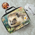 Lunch bag with hedgehog design and 'Emma' personalized name on a table with a drink and utensils.