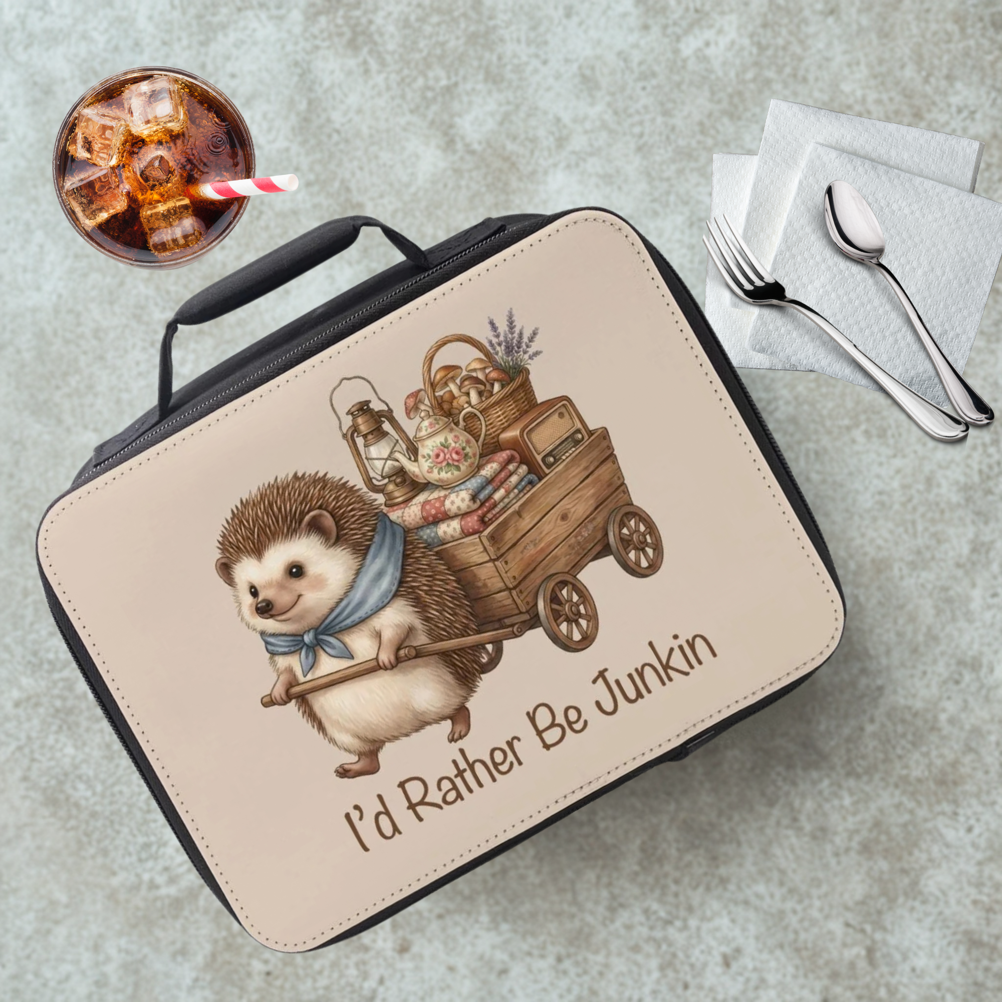 Lunch bag with hedgehog design and text on a cafeteria table with a drink and utensils.