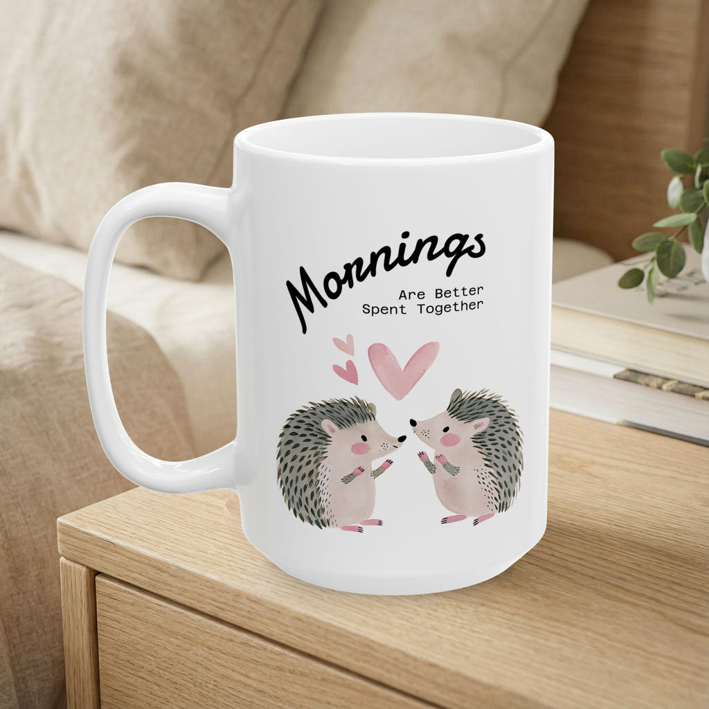 15 oz ceramic mug with a hedgehog couple design sitting on a bedside table.