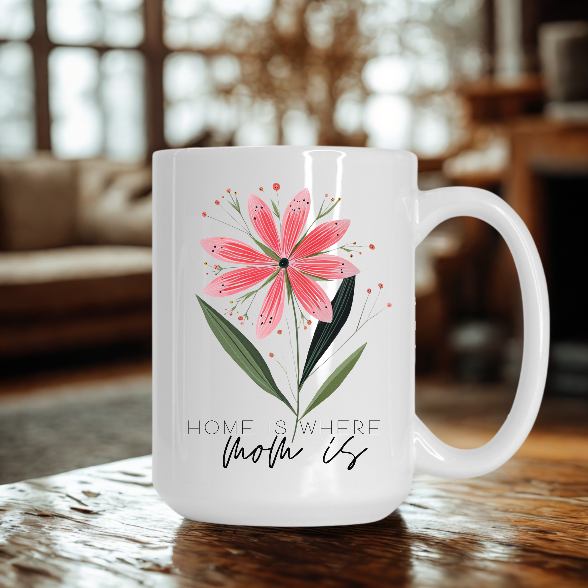 White 15oz mug with pink floral design and 'Home is where mom is' text on a wooden surface.
