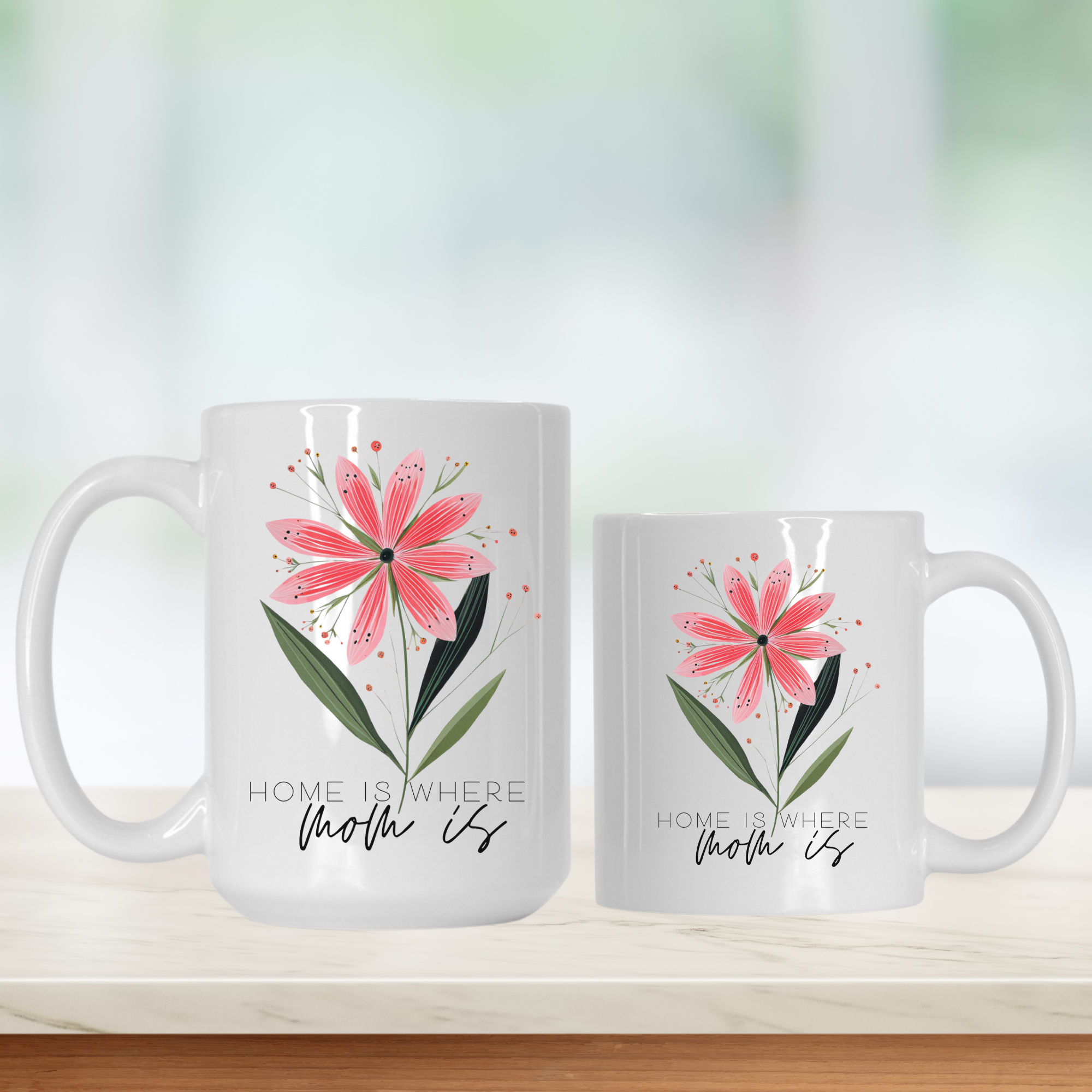 15oz and 11oz white ceramic mugs with floral design and 'Home is where mom is' text on a light background