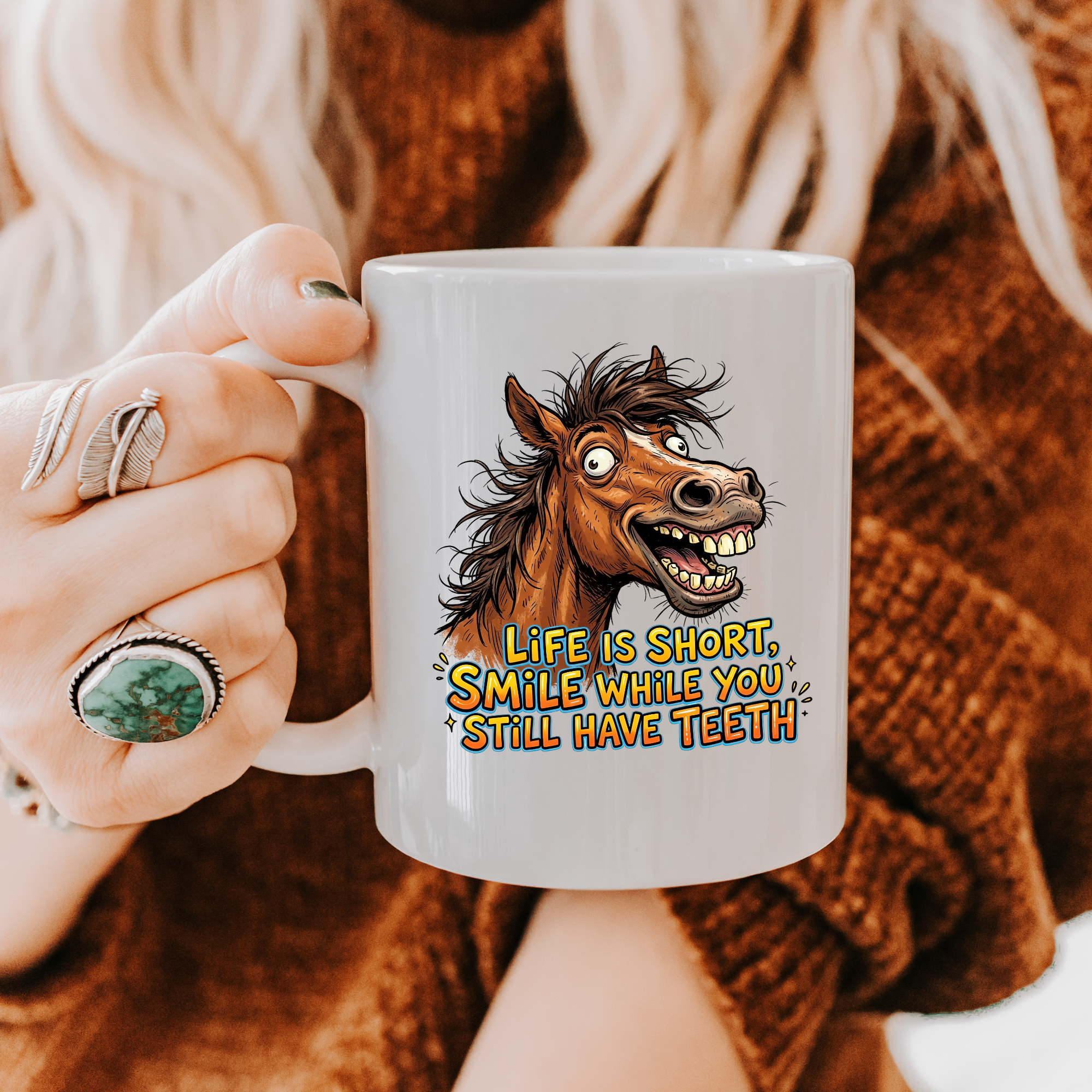 Person holding a mug with a horse graphic and text 'Life is short, smile while you still have teeth' against a brown textured background.