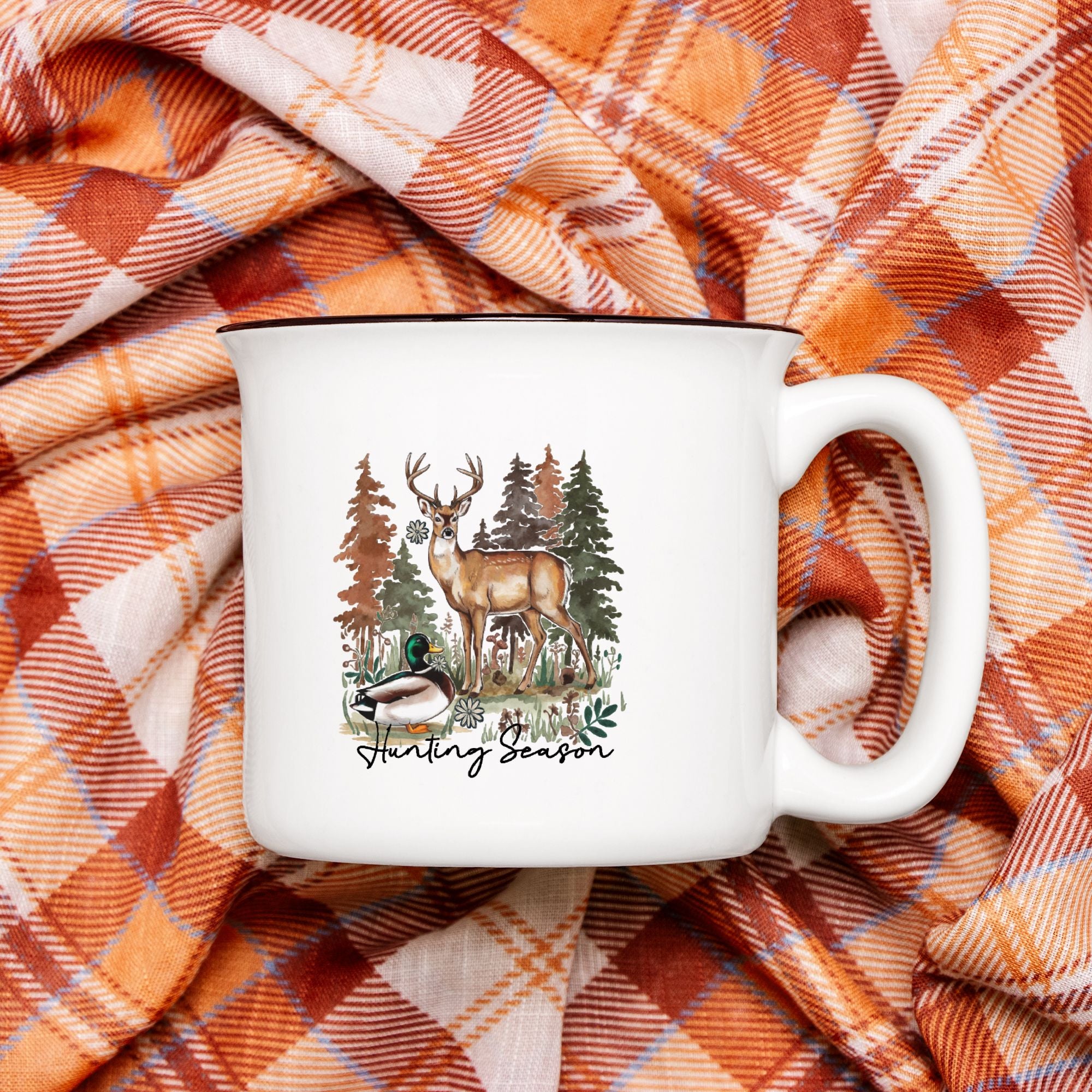 White mug with nature-themed design on a plaid fabric background