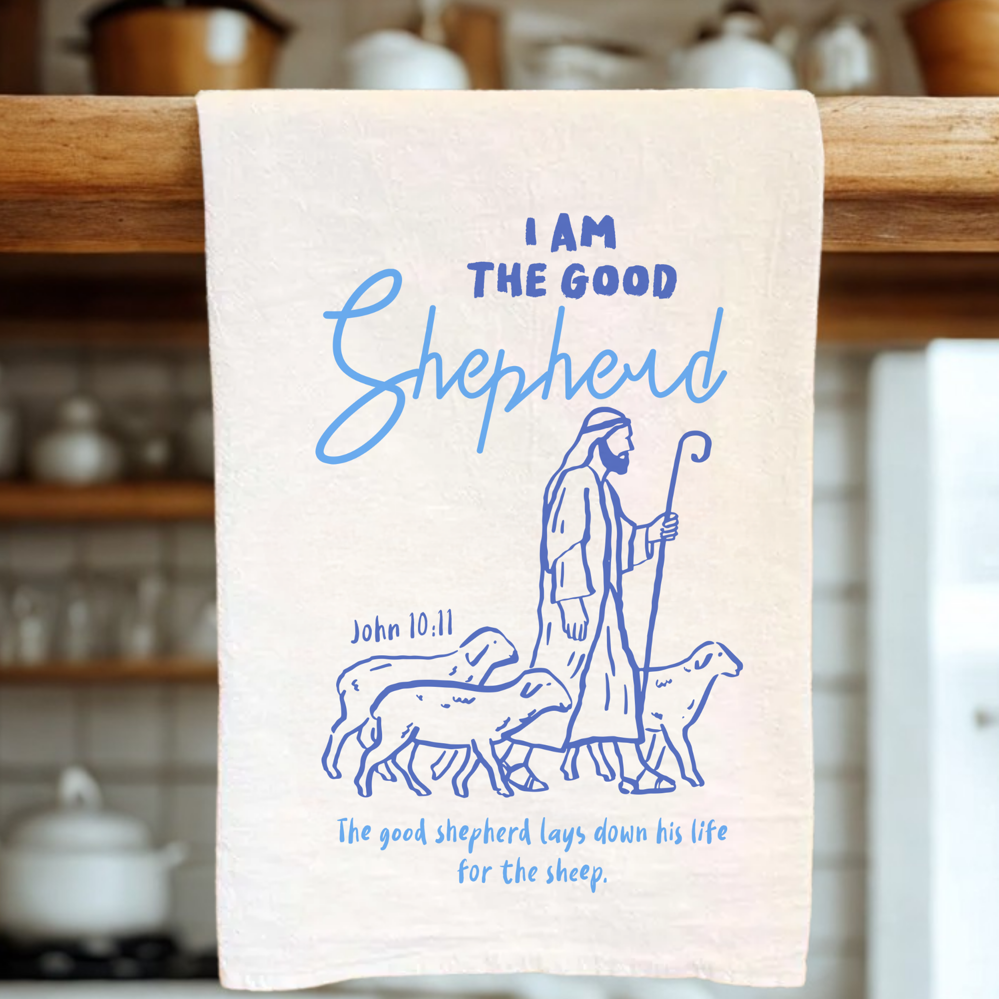 White tea towel with blue illustration of a shepherd and text on a wooden rack.