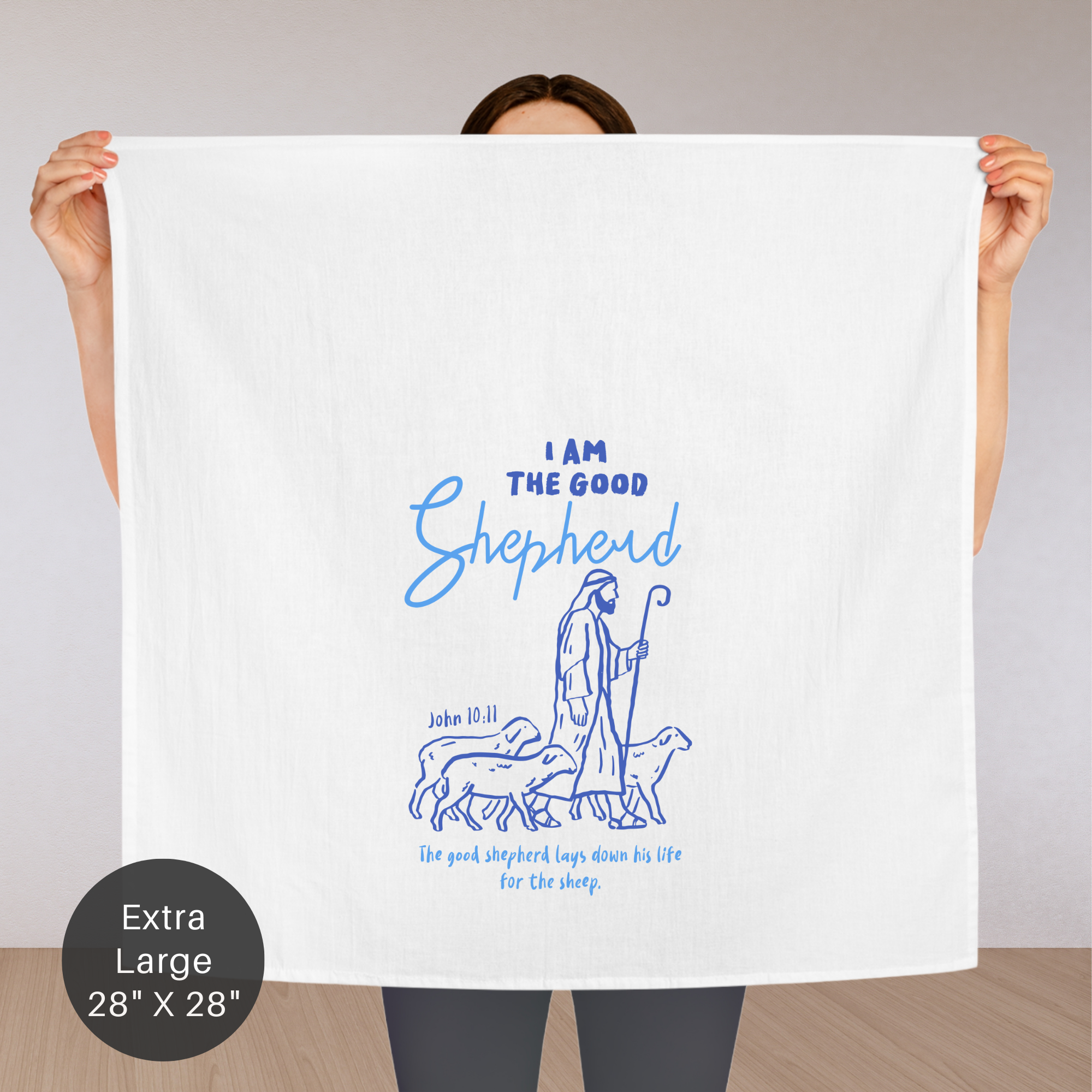 Person holding an extra large white tea towel with blue text and illustration of a shepherd.