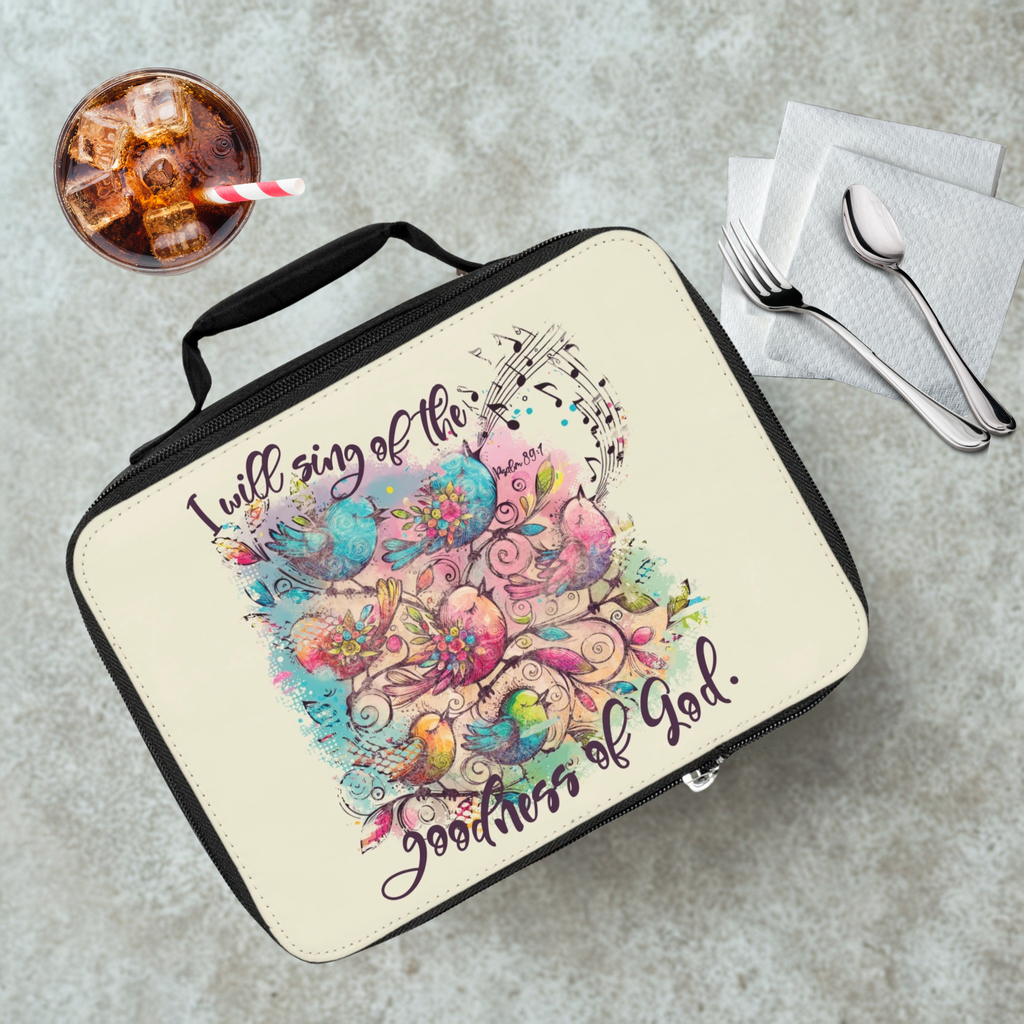  insulated lunch bag with colorful bird design and text 'I will sing of the goodness of God' on a cafeteria table with a drink and eating utensils