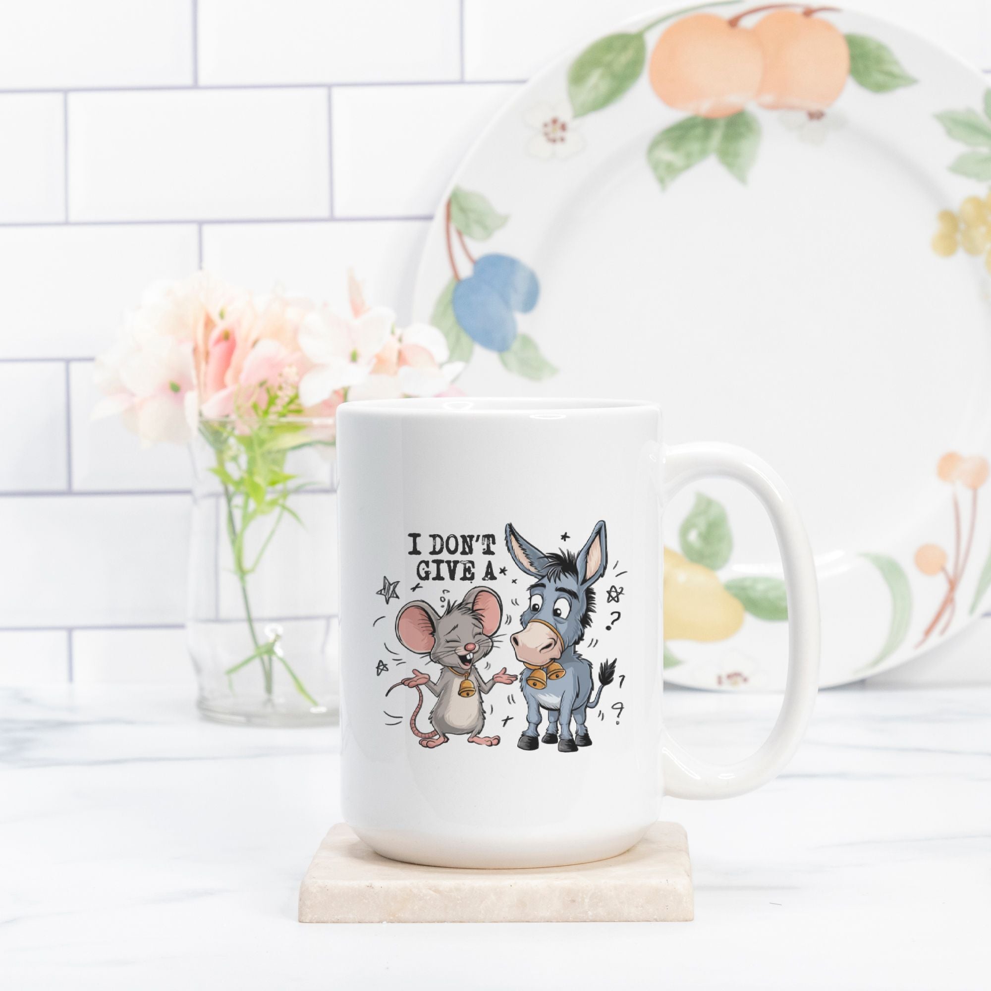 White mug with cartoon characters and text on a white surface with a decorative plate in the background.