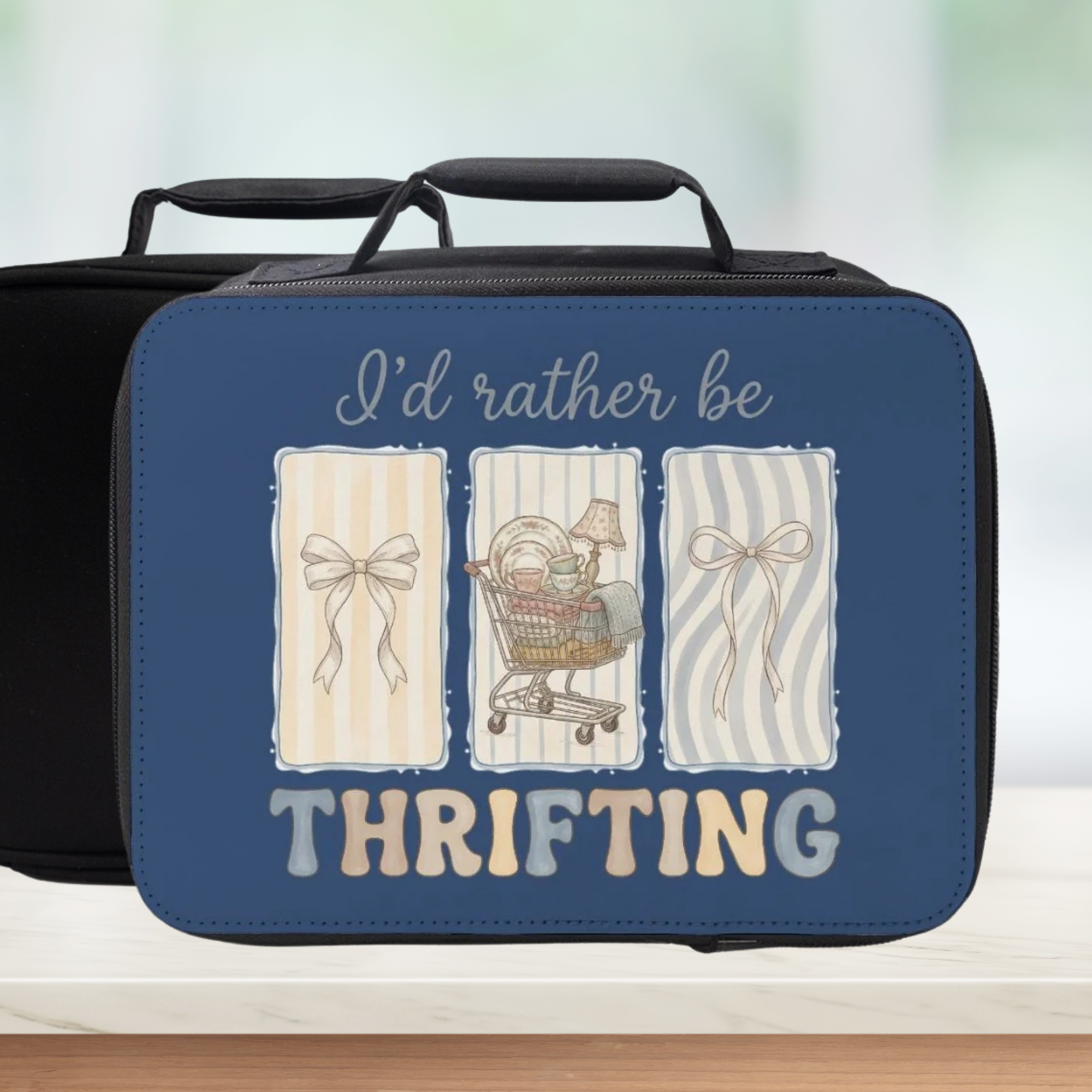Blue lunch box with 'I'd rather be thrifting' text and illustrations on a blurred background