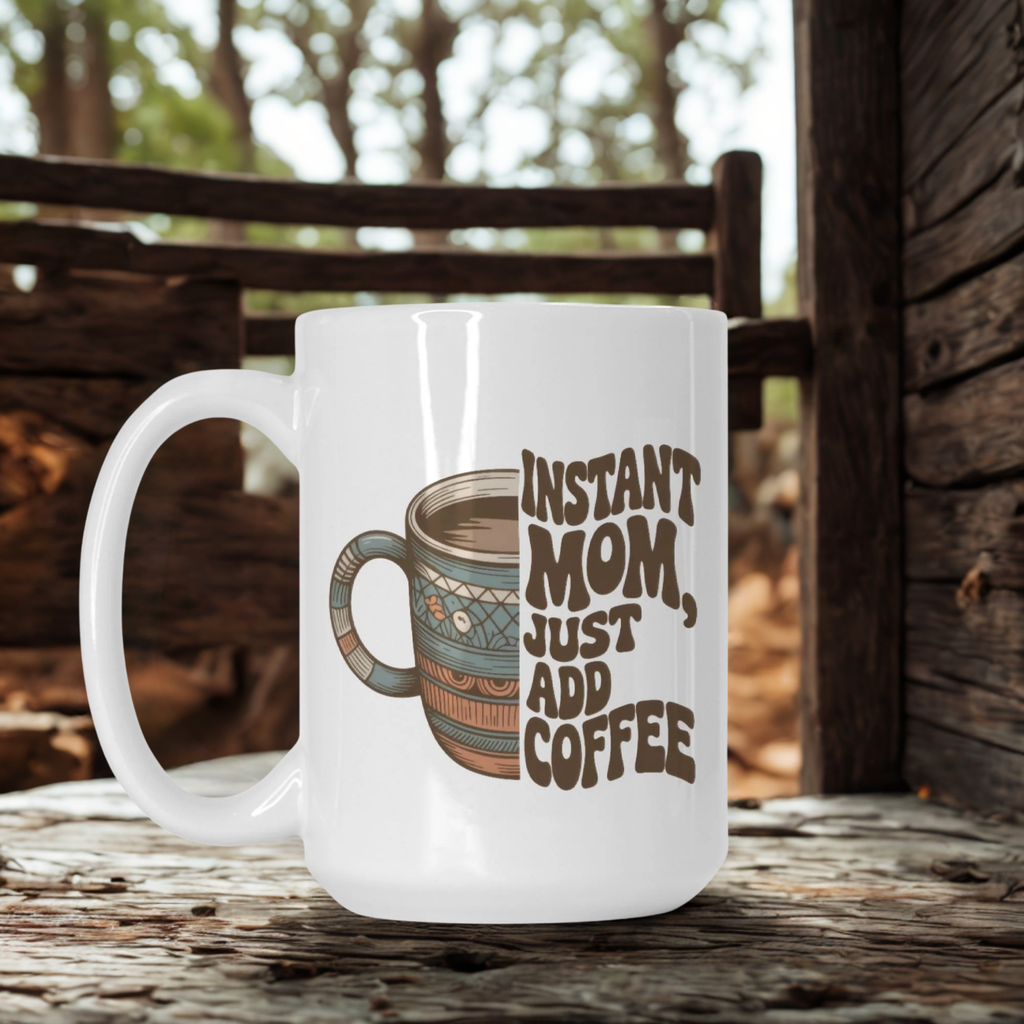 White mug with a design and text 'Instant Mom, Just Add Coffee' on a wooden surface.