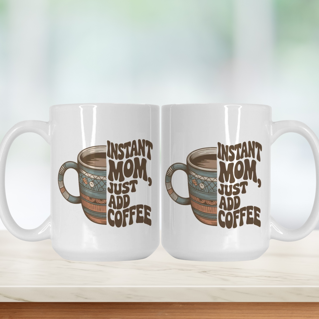 Two white mugs with a graphic of a coffee cup and text 'Instant Mom, Just Add Coffee' on a light background.