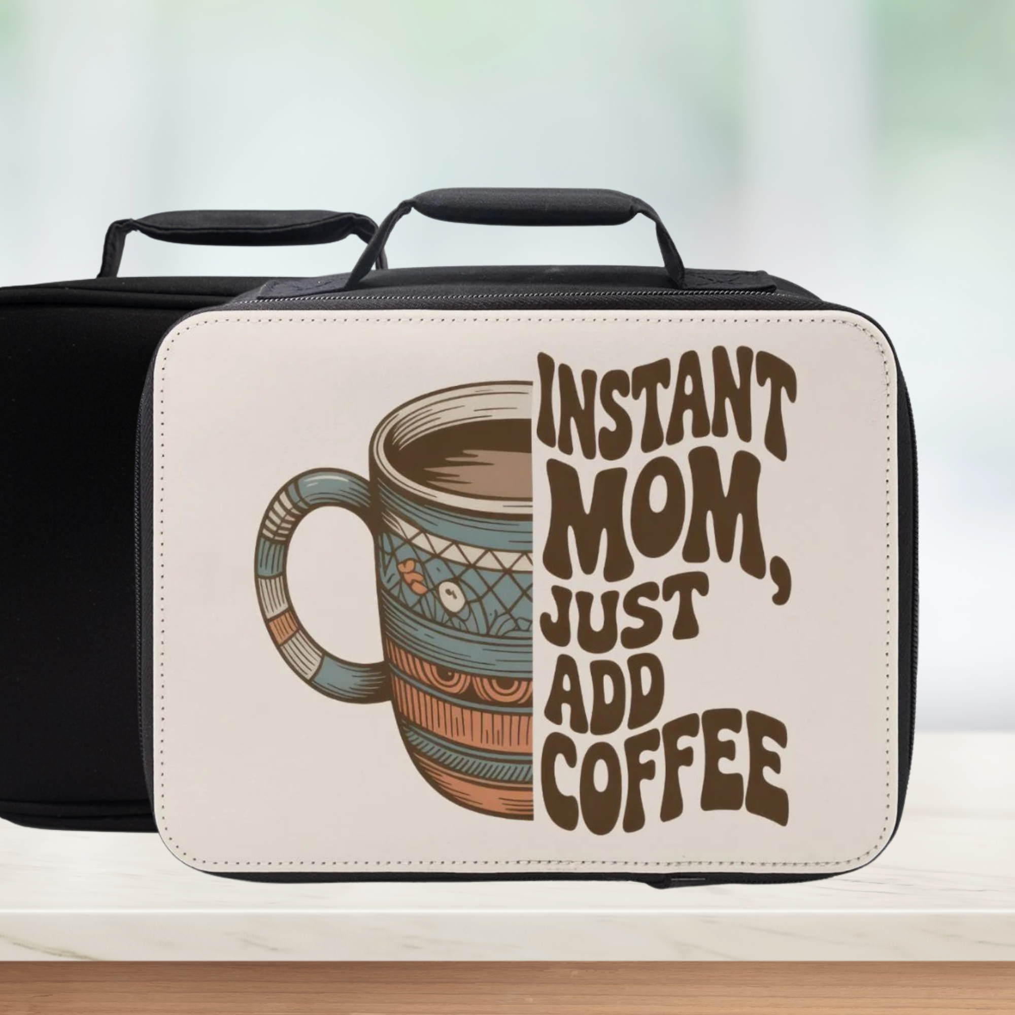Black lunch box with a graphic of a coffee mug and text 'Instant Mom, Just Add Coffee' on a blurred background.