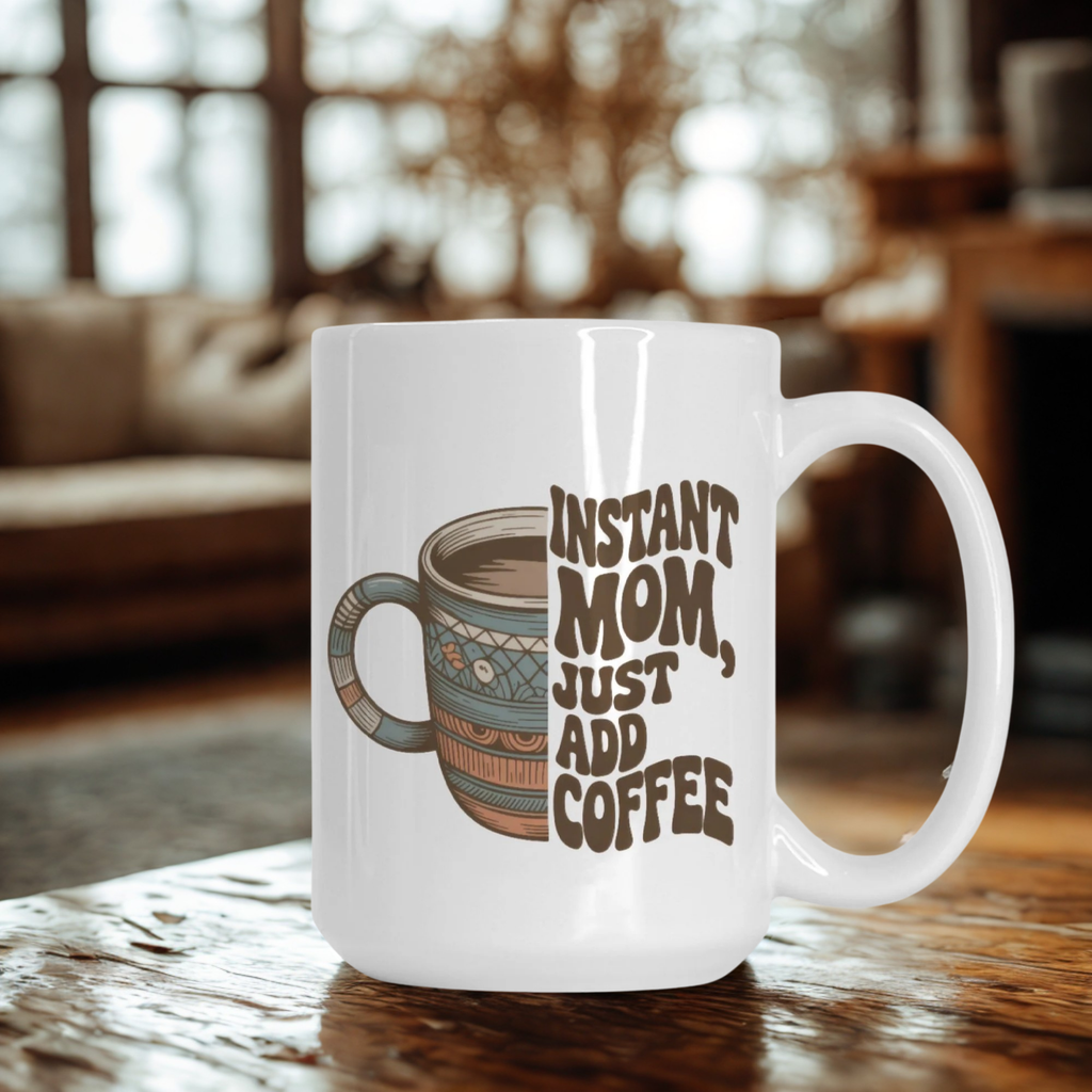 White mug with coffee graphic and text 'Instant Mom, Just Add Coffee' on a wooden table.