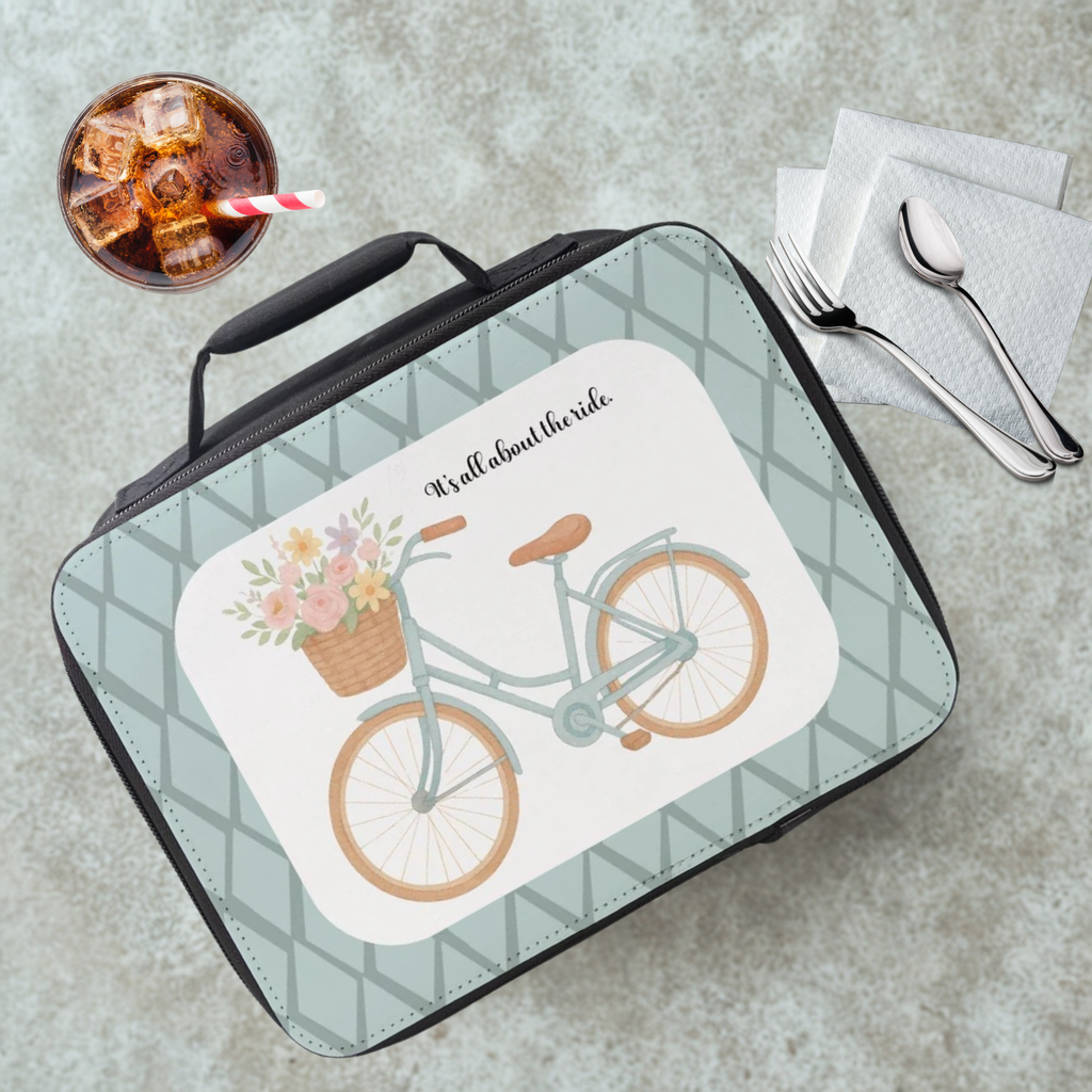 Lunch box with bicycle design and text on a cafeteria table with a drink and utensils.
