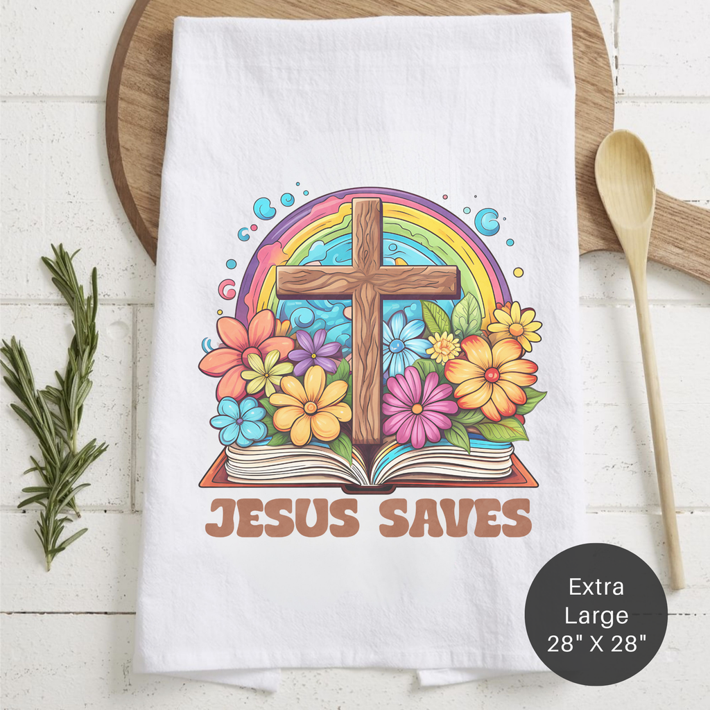 White tea towel with a colorful design of a cross, rainbow, and flowers on a wooden surface.