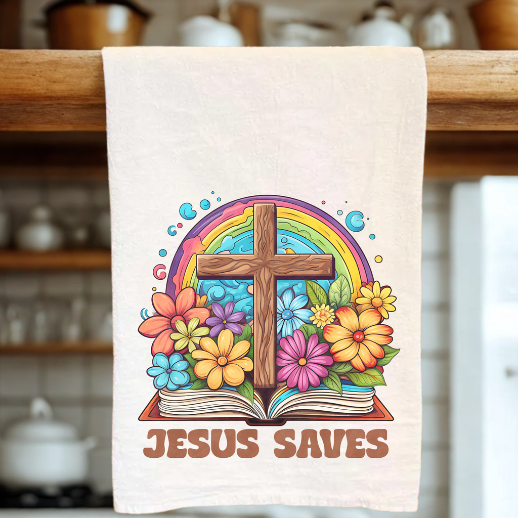 Tea towel with a cross, rainbow, and flowers design on a wooden rack.