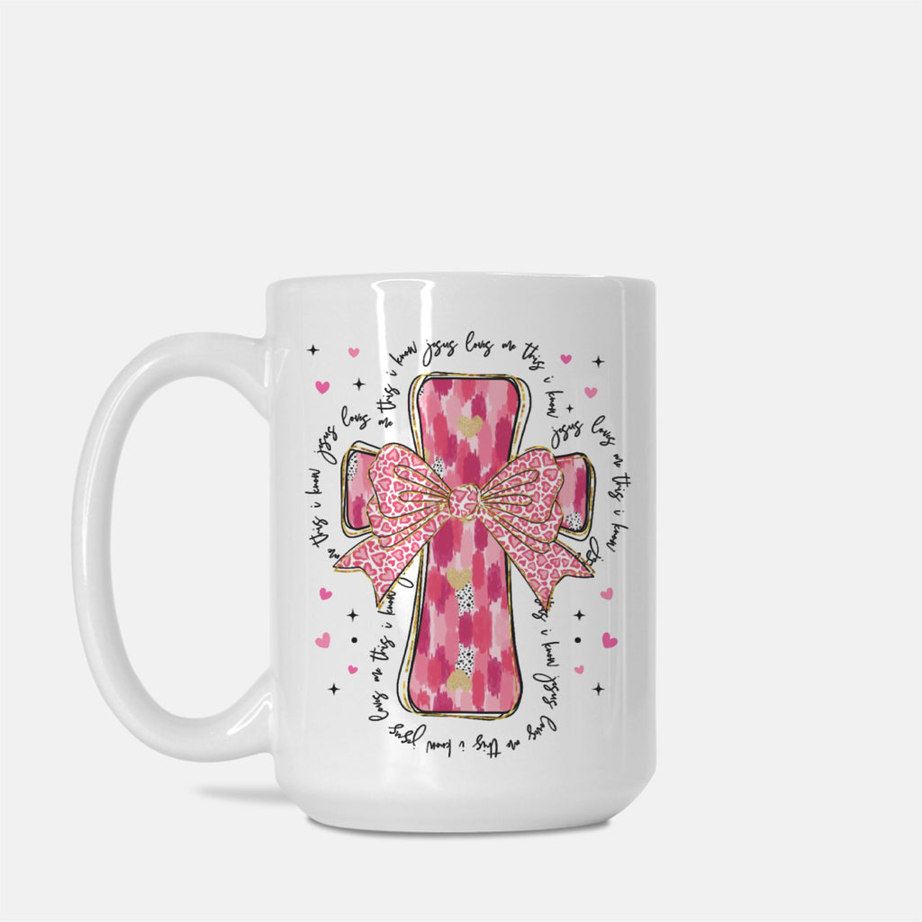 White mug with pink cross and bow design on a white background