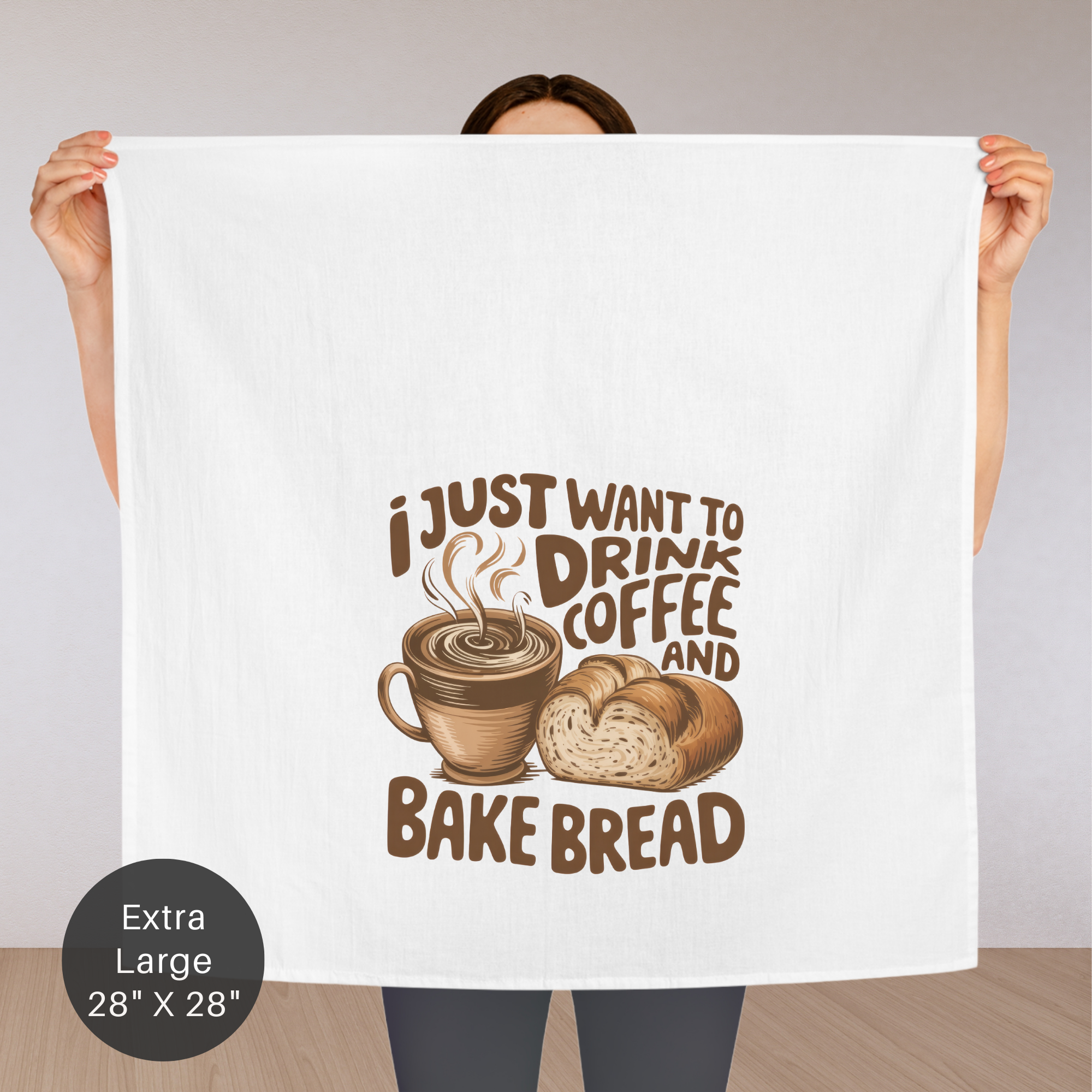 Person holding an extra large tea towel with coffee and bread design and text.