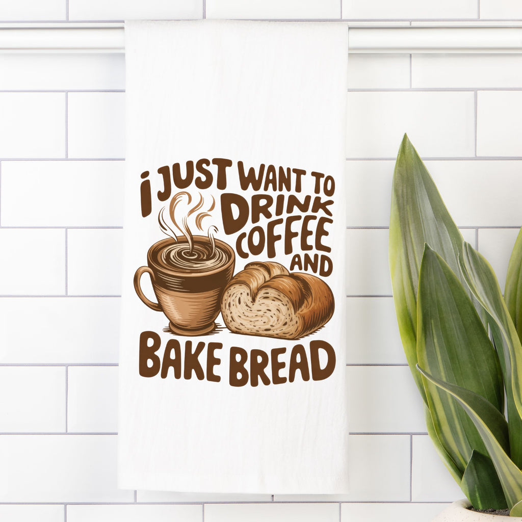 Decorative tea towel with a coffee cup and bread design and text 'I just want to drink coffee and bake bread' on a white tiled wall.