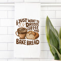 Decorative tea towel with a coffee cup and bread design and text 'I just want to drink coffee and bake bread' on a white tiled wall.