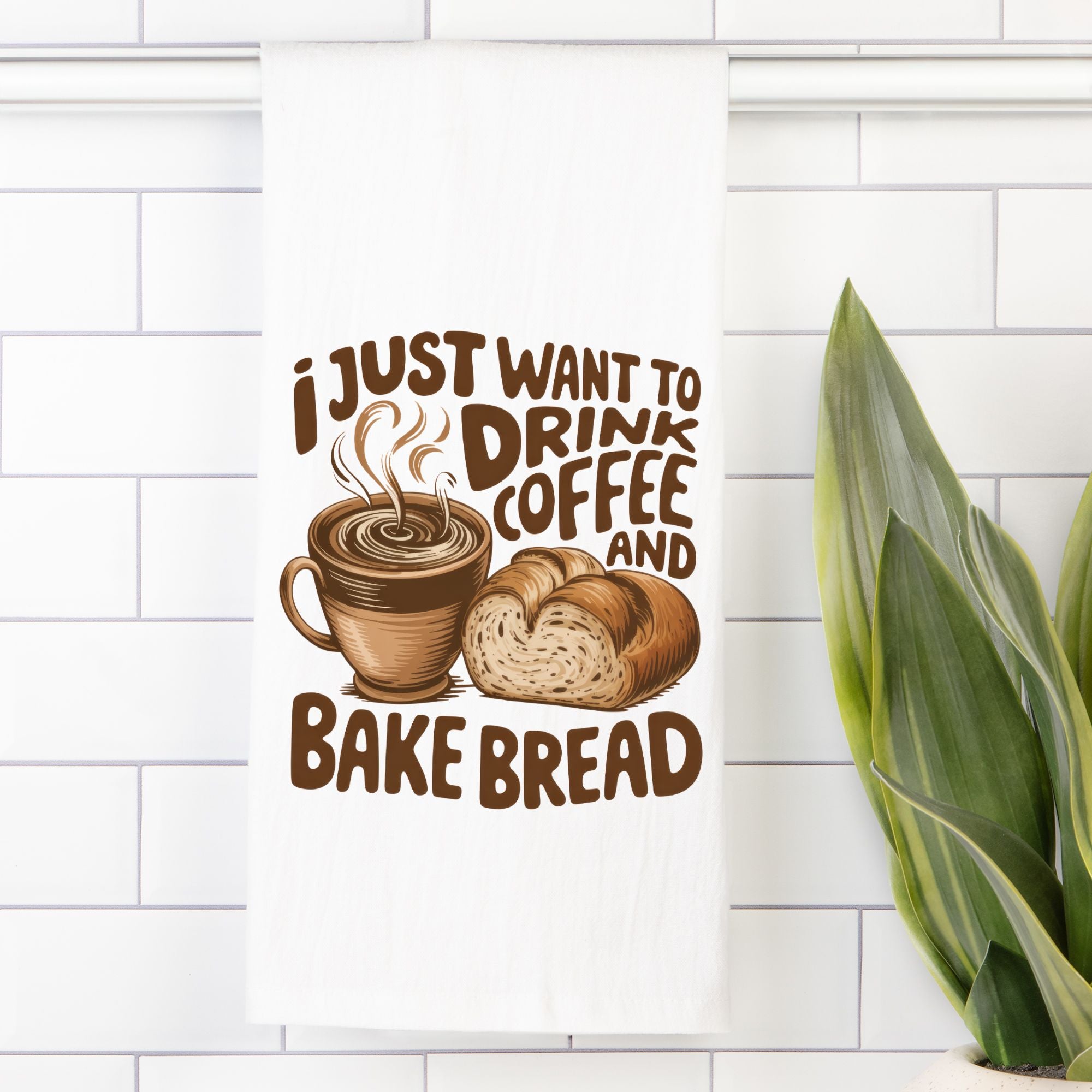 Decorative tea towel with a coffee cup and bread design and text 'I just want to drink coffee and bake bread' on a white tiled wall.