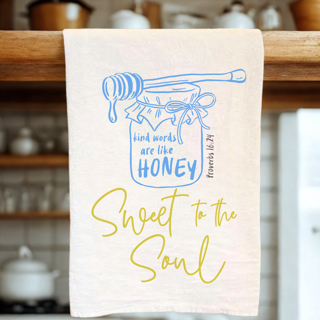 Kitchen towel with honey jar and text design on a wooden rack.