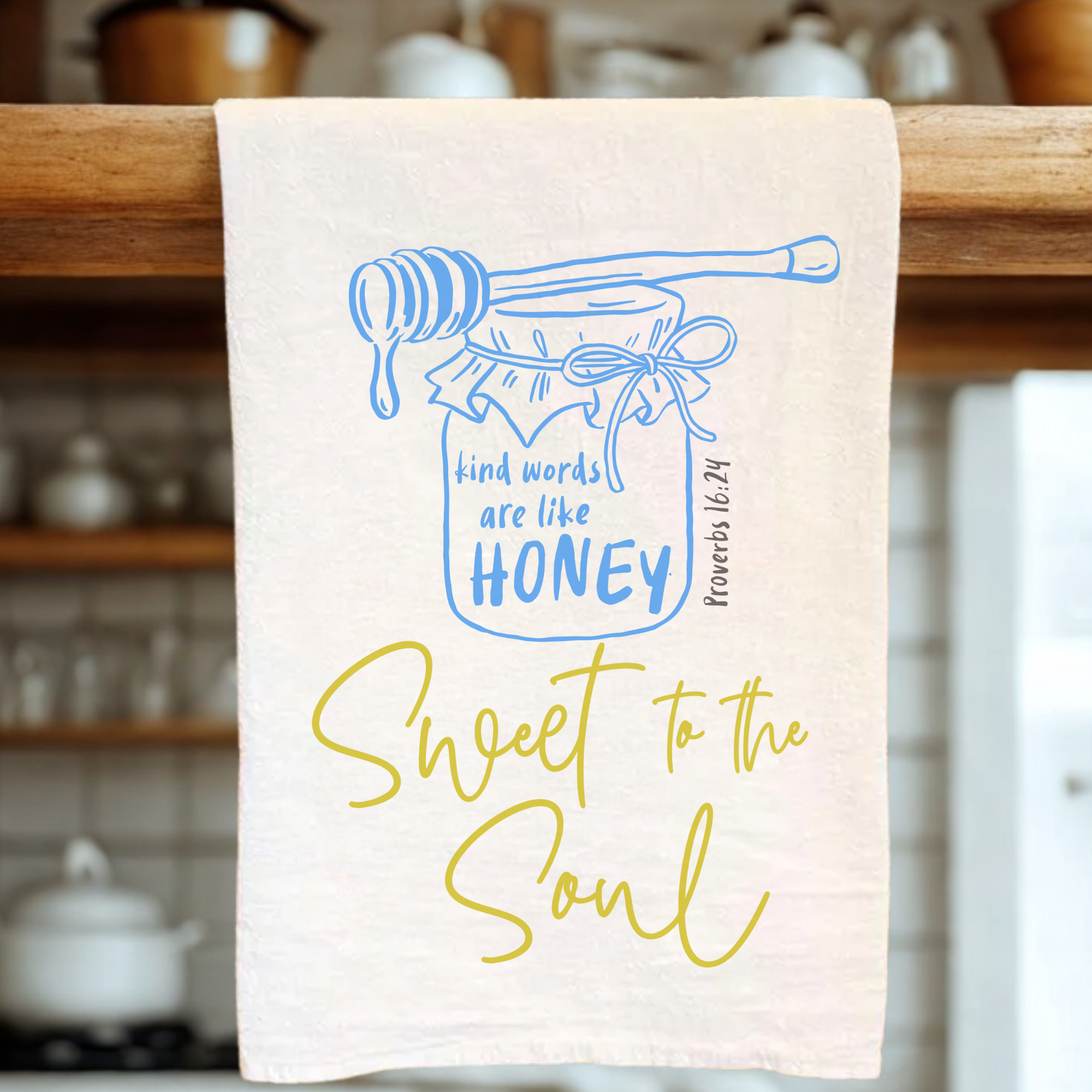 Kitchen towel with honey jar and text design on a wooden rack.