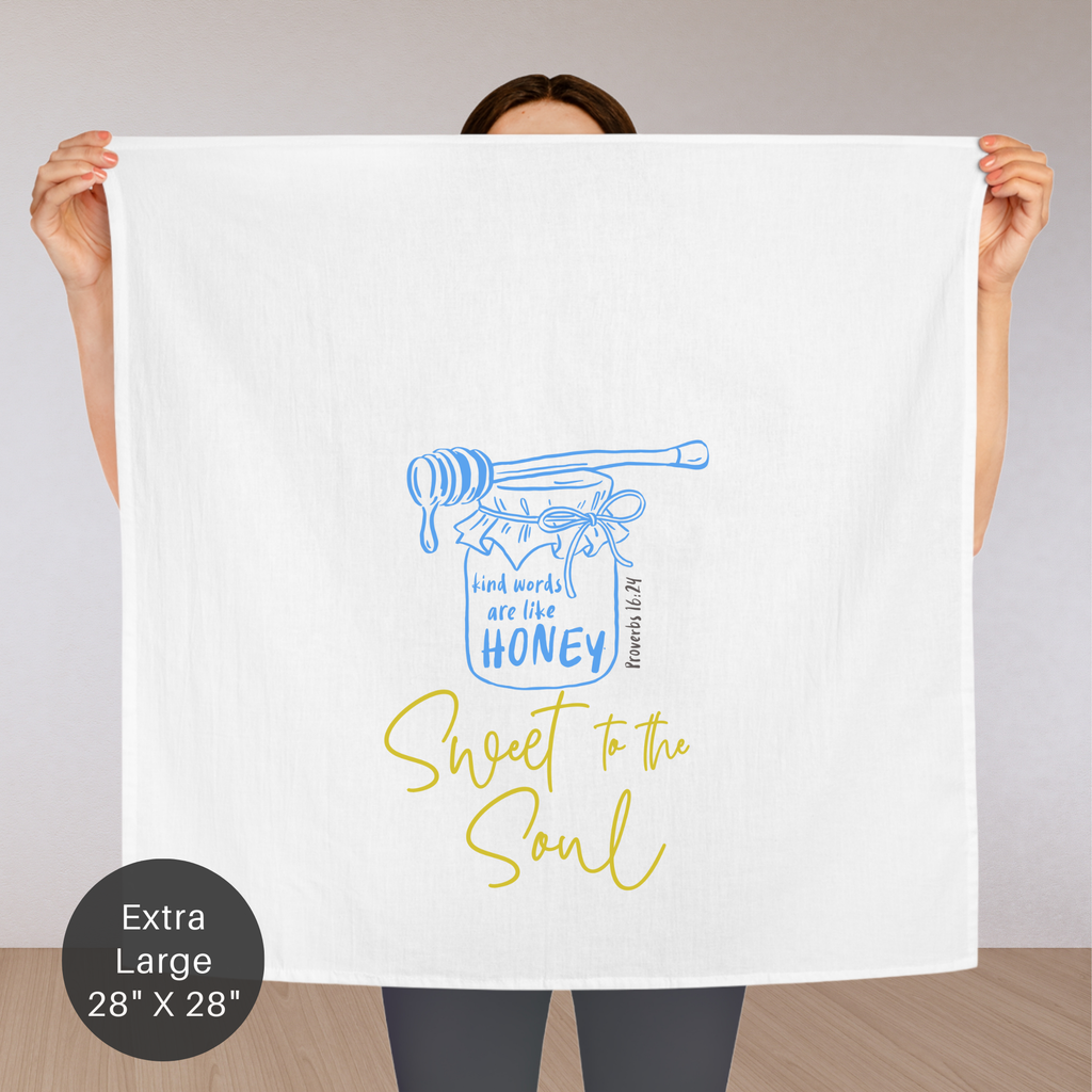 Person holding an extra large white tea towel with a blue and yellow design and text.