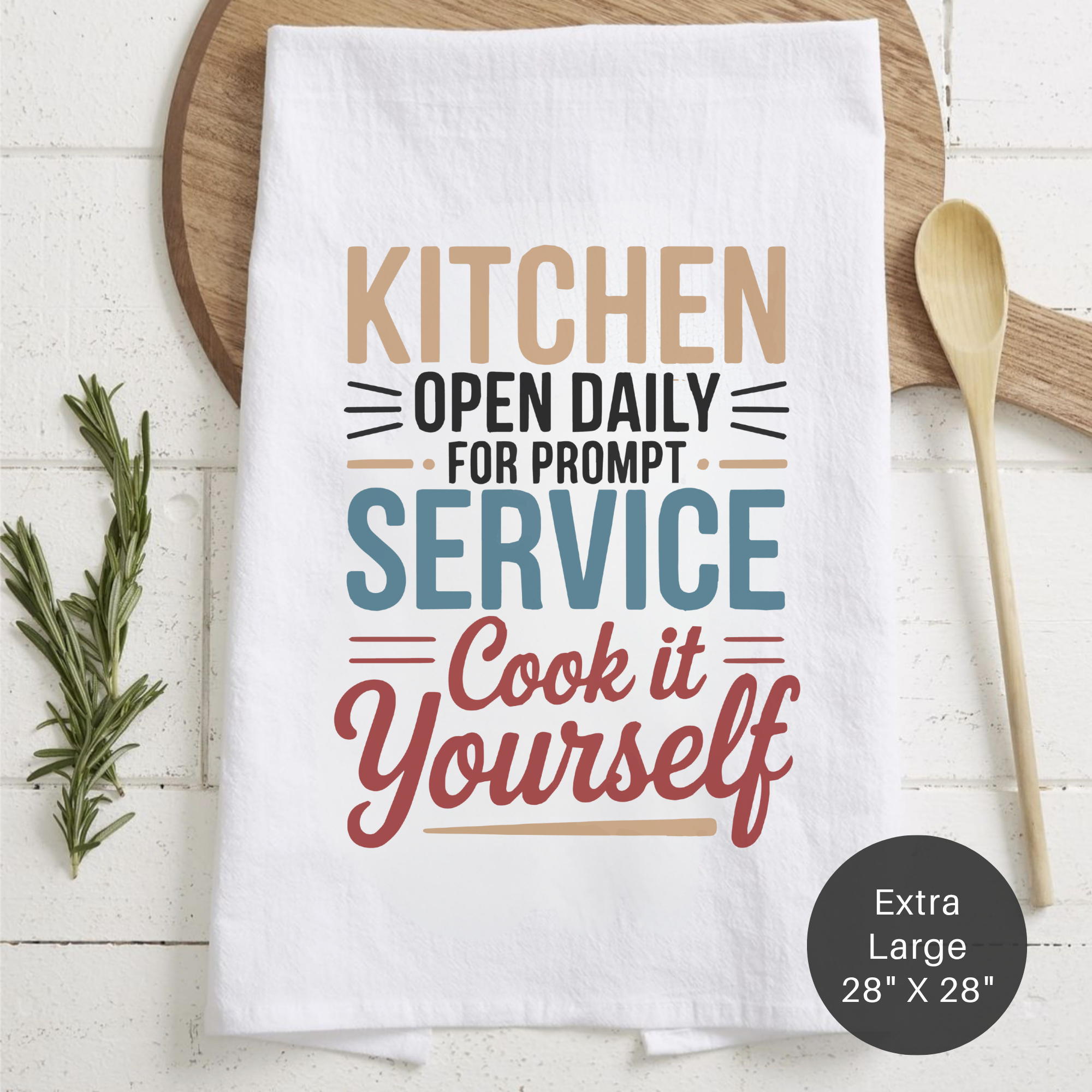 White tea towel with humorous kitchen quote on a wooden surface with a spoon and rosemary.
