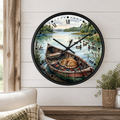 A round wall clock with a black frame and a scenic illustration of a cat sleeping in a rowboat on a lake, mounted on a white shiplap wall above a wooden table with a plant.