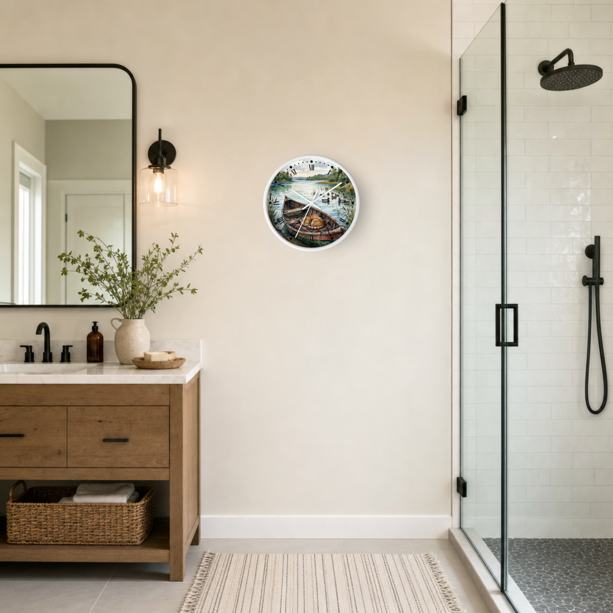 A round wall clock with a scenic cat sleeping in a boat illustration hangs on a beige wall in a modern bathroom setting with a wooden vanity, mirror, and glass shower enclosure.