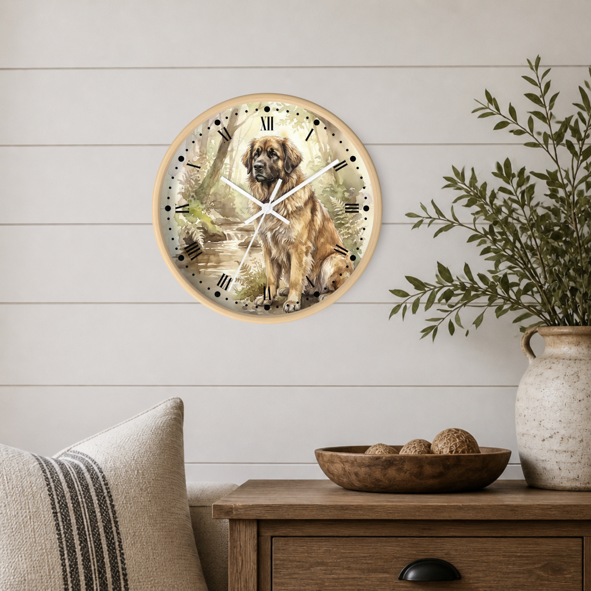 A round wall clock featuring a detailed illustration of a Leonberger dog in a forest, mounted on a white shiplap wall above a wooden side table with a plant and decorative bowl.