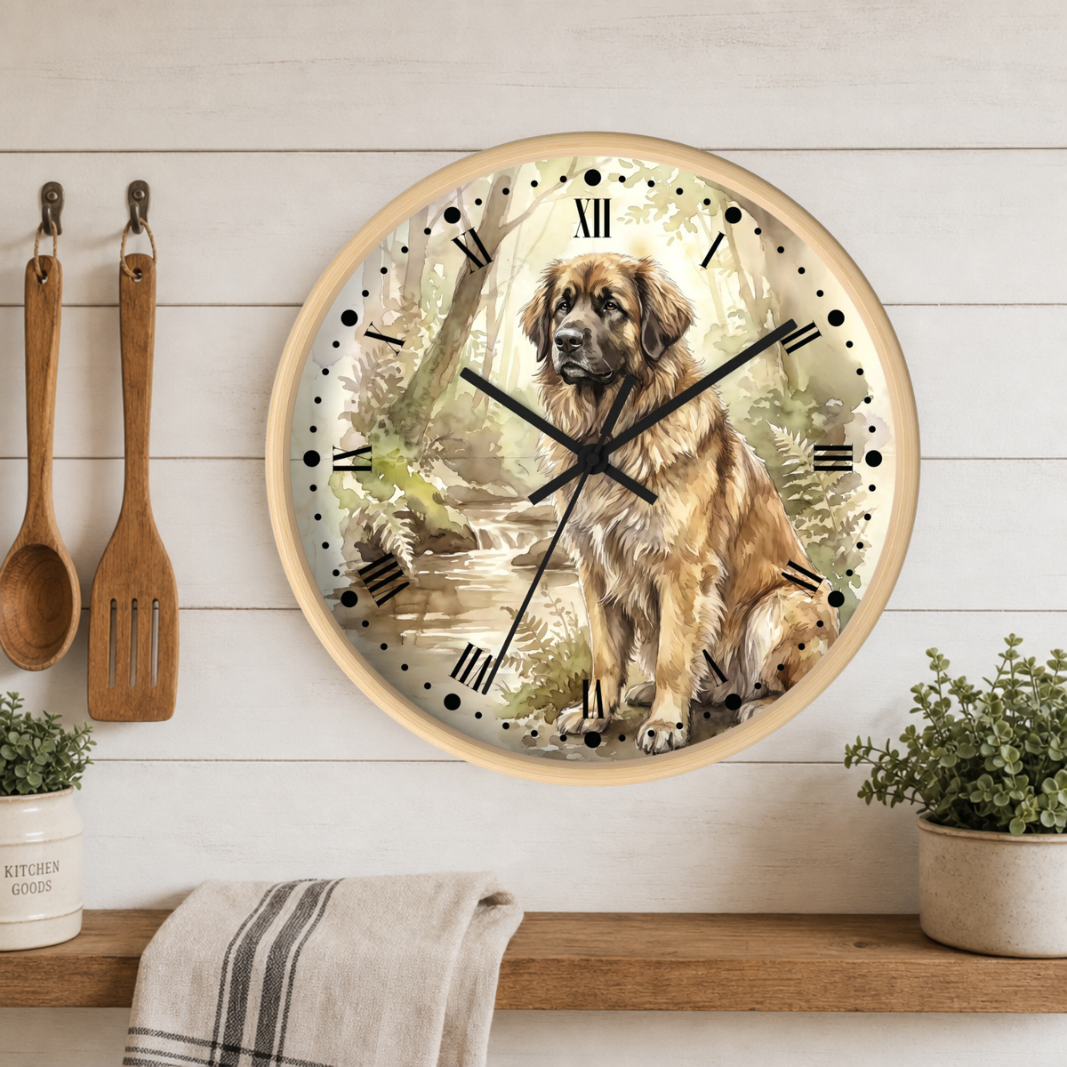 A round wall clock with a light wood frame hangs on a white shiplap wall above a wooden shelf. The clock face features a detailed illustration of a Leonberger dog sitting by a stream in a forest.