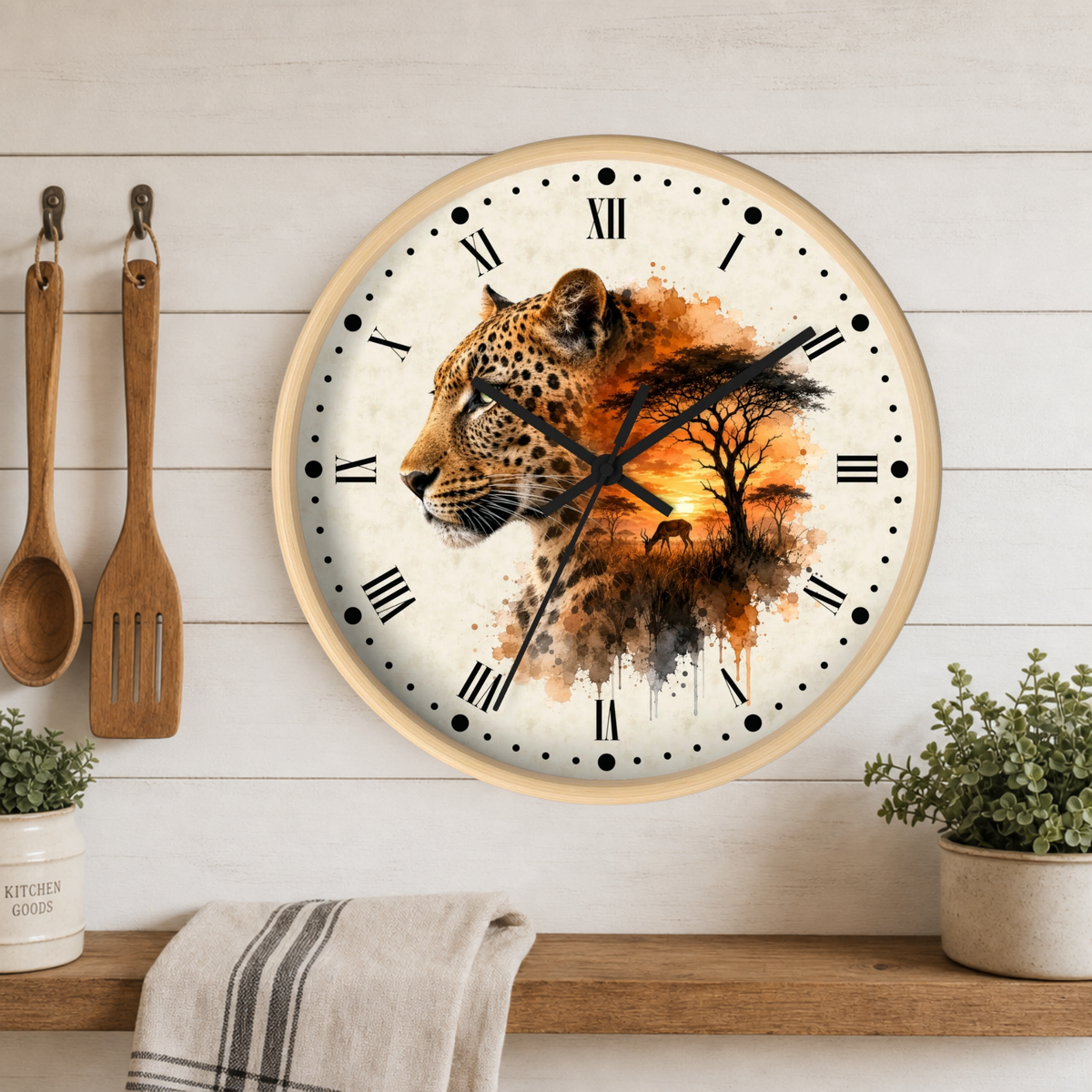 A round wall clock with a leopard and sunset watercolor design, mounted on a white wood-paneled wall above a shelf with plants and utensils.