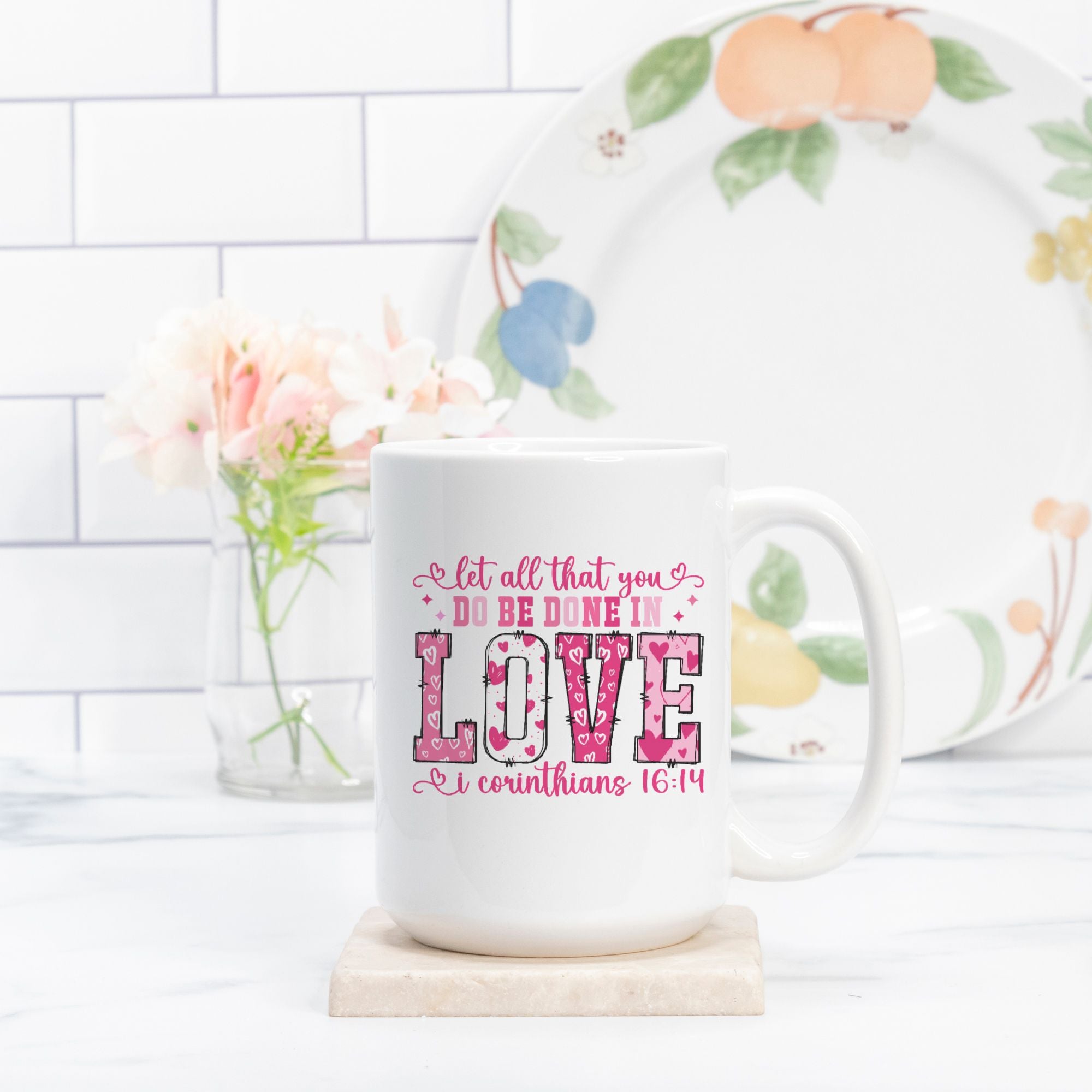 White mug with inspirational quote and floral design on a white surface with a decorative plate in the background.